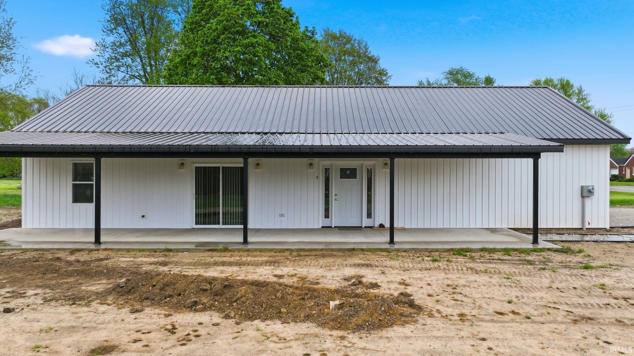 Contemporary single-story residence featuring a dark metal roof and white board-and-batten siding