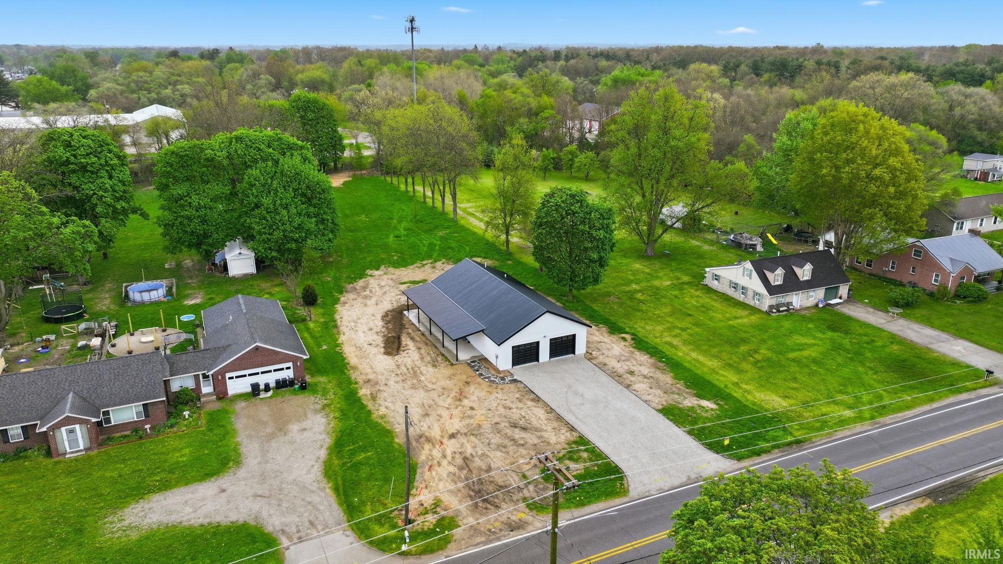 Newly constructed residence featuring a black metal roof, white siding, and black garage doors