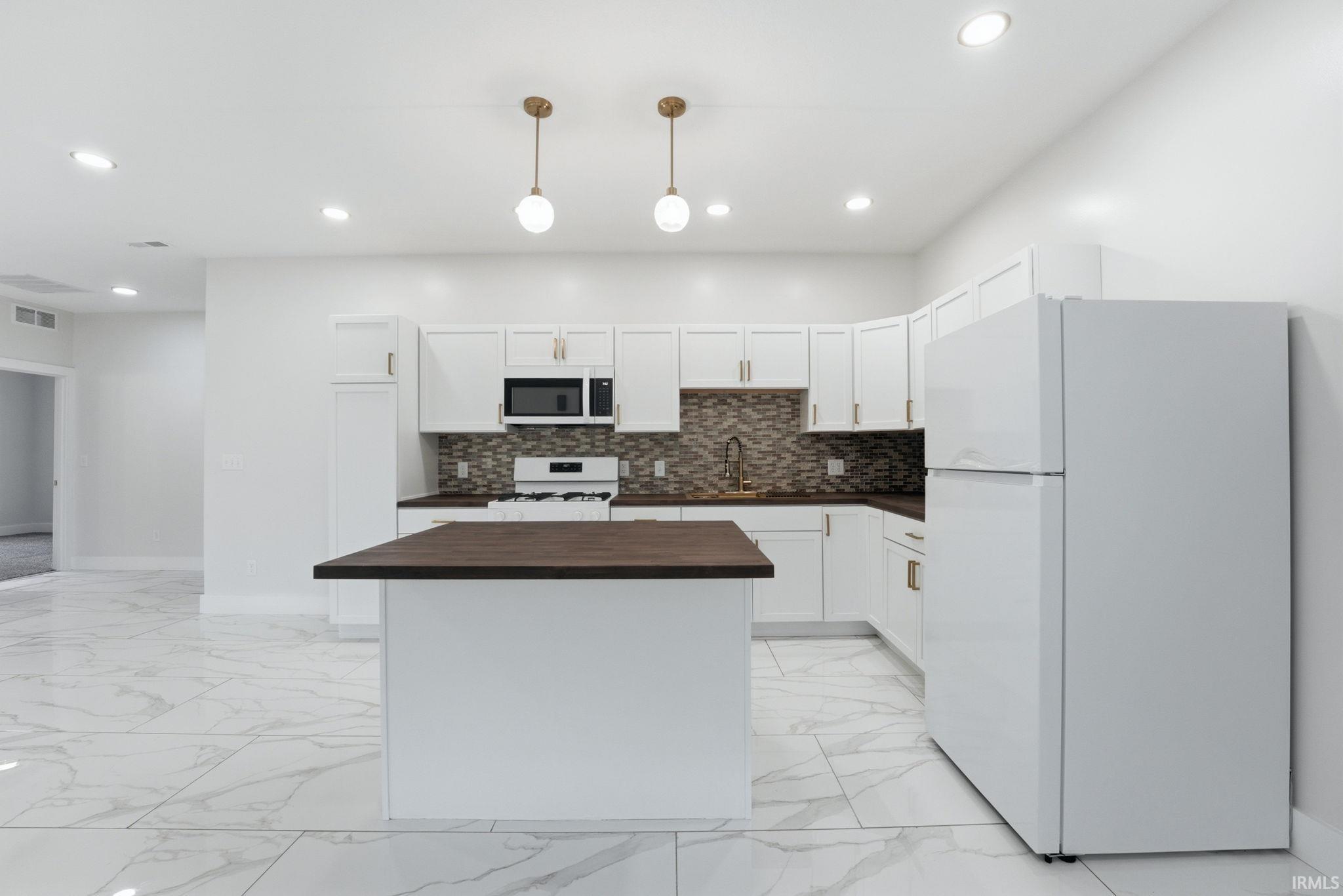Modern kitchen featuring white cabinetry, dark countertops, and a patterned tile backsplash