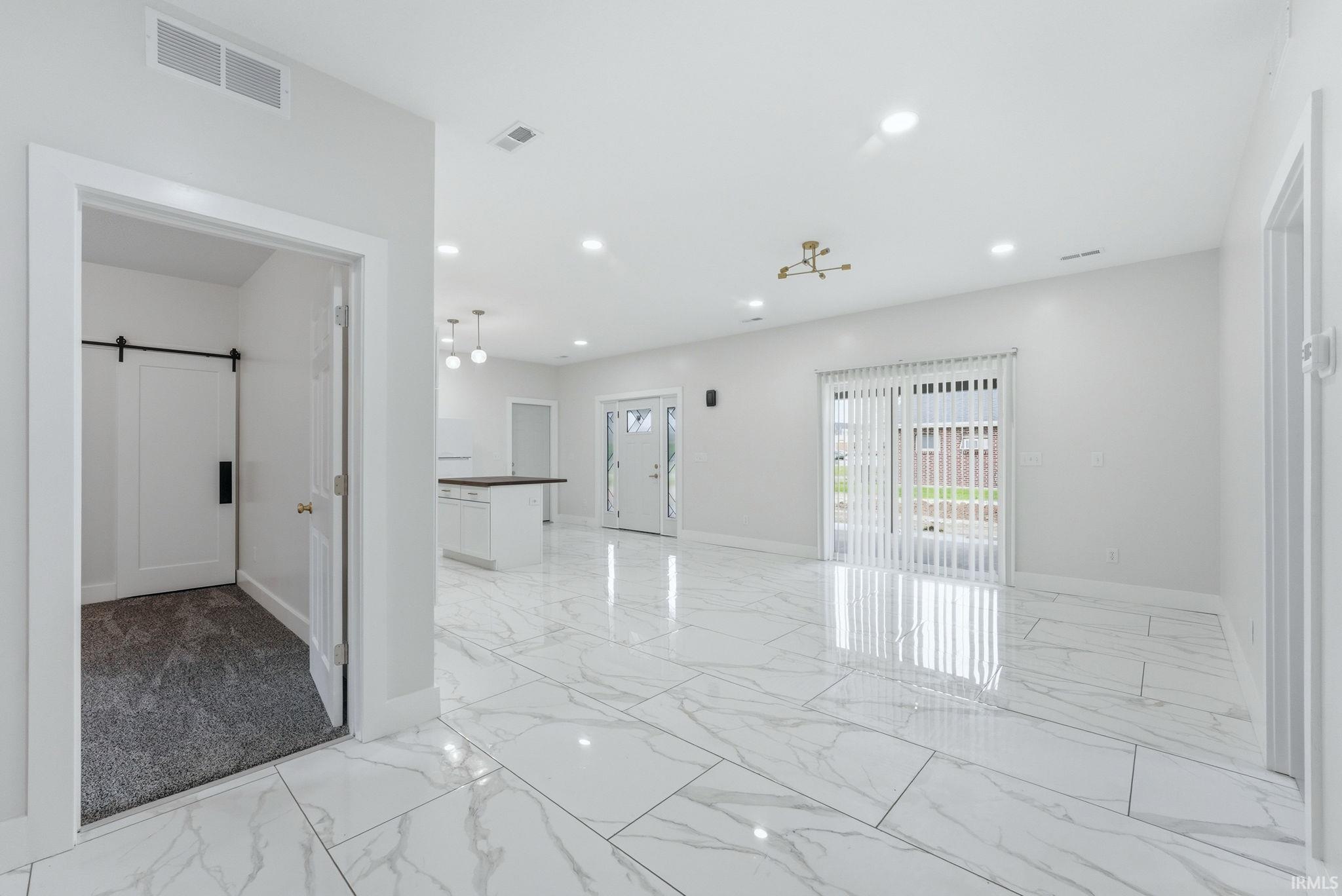 Expansive living area featuring white marble-look tile flooring, recessed lighting, and a modern gold-finish chandelier
