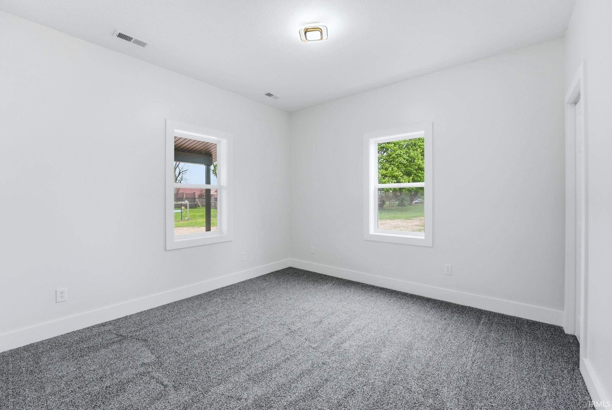 Carpeted room featuring white walls, white trim, two windows with white frames, and a flush-mount ceiling light fixture
