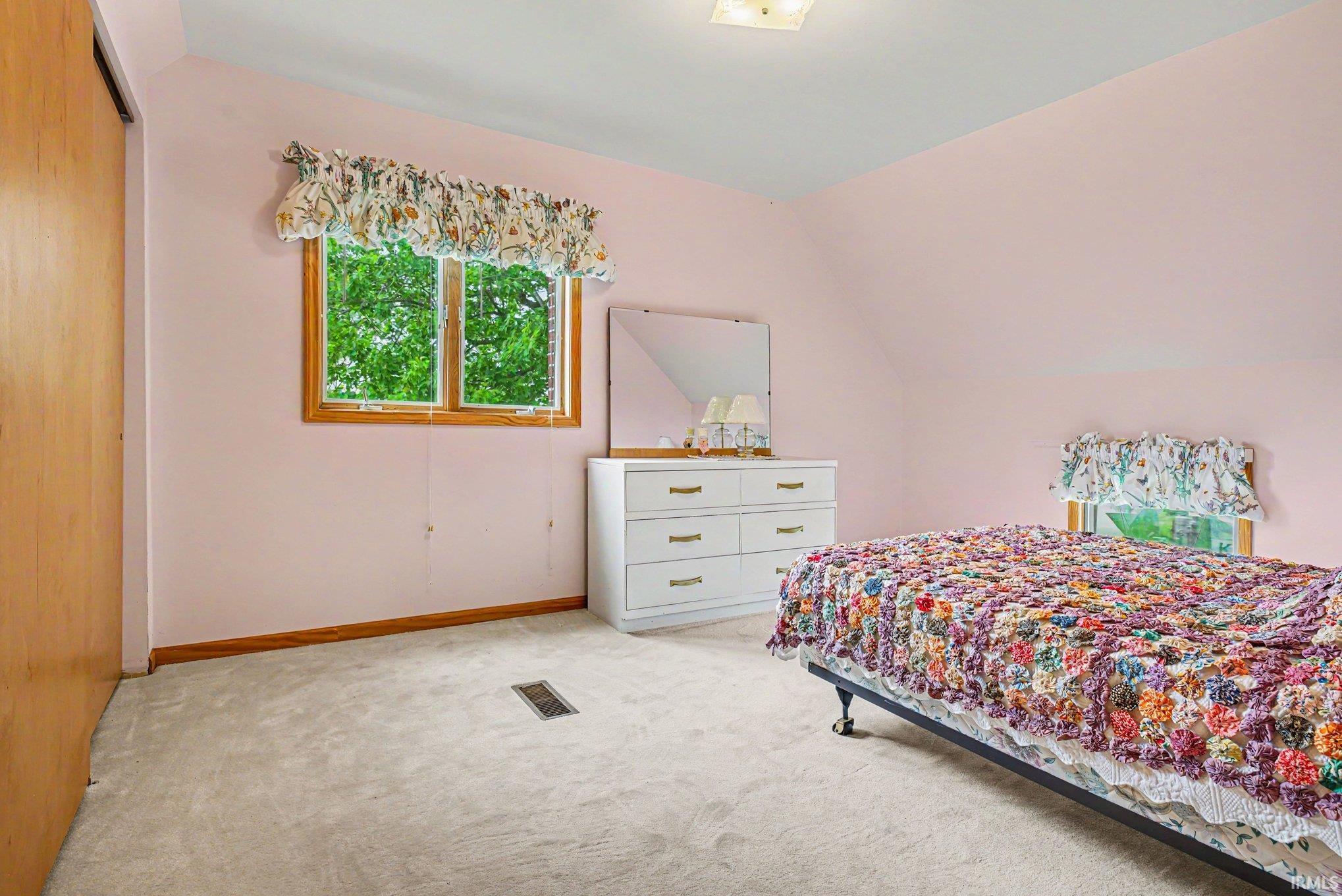 Carpeted room with a wooden framed window, light wood baseboards, and a flush-mounted ceiling light fixture