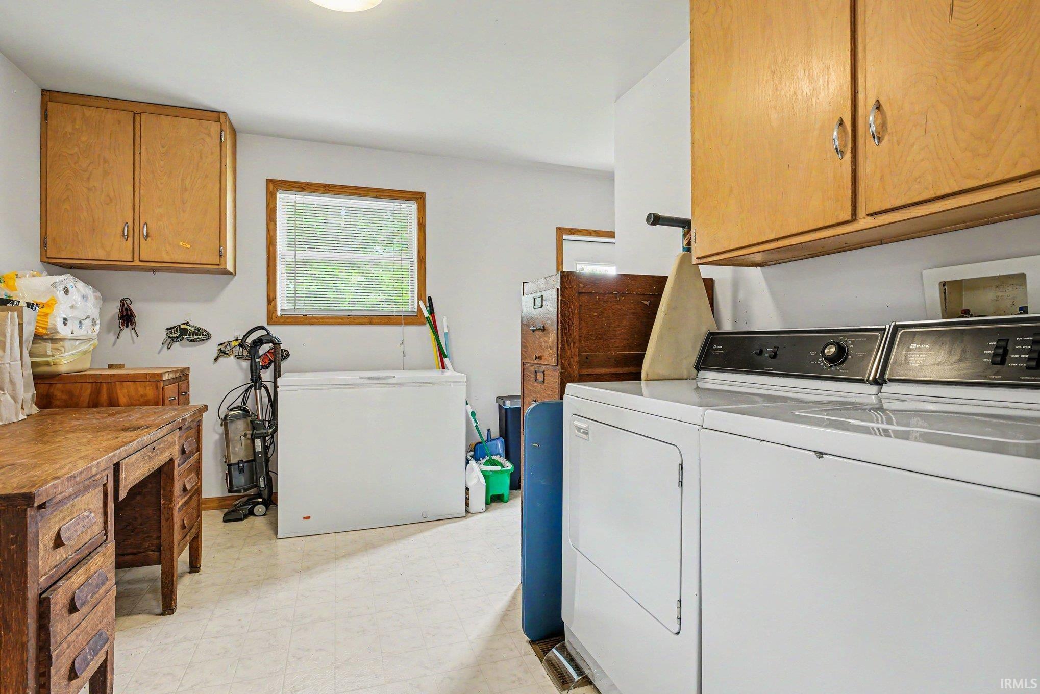 Dedicated utility space featuring a window, overhead cabinetry, and vinyl flooring