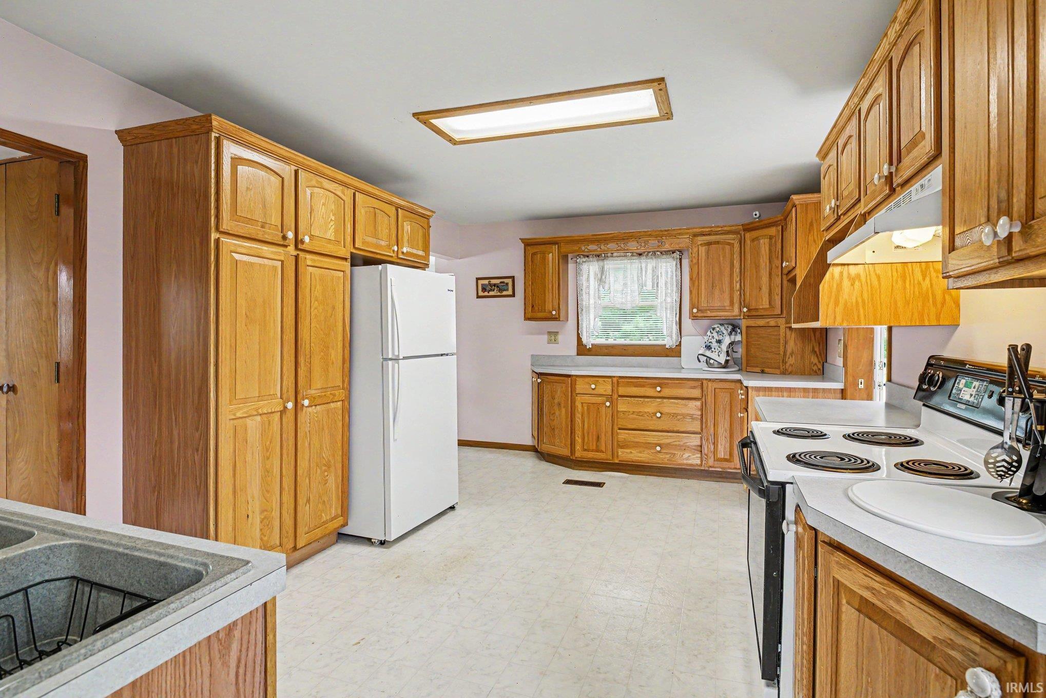 Kitchen featuring wood cabinetry, white countertops, vinyl flooring, and a window with natural light