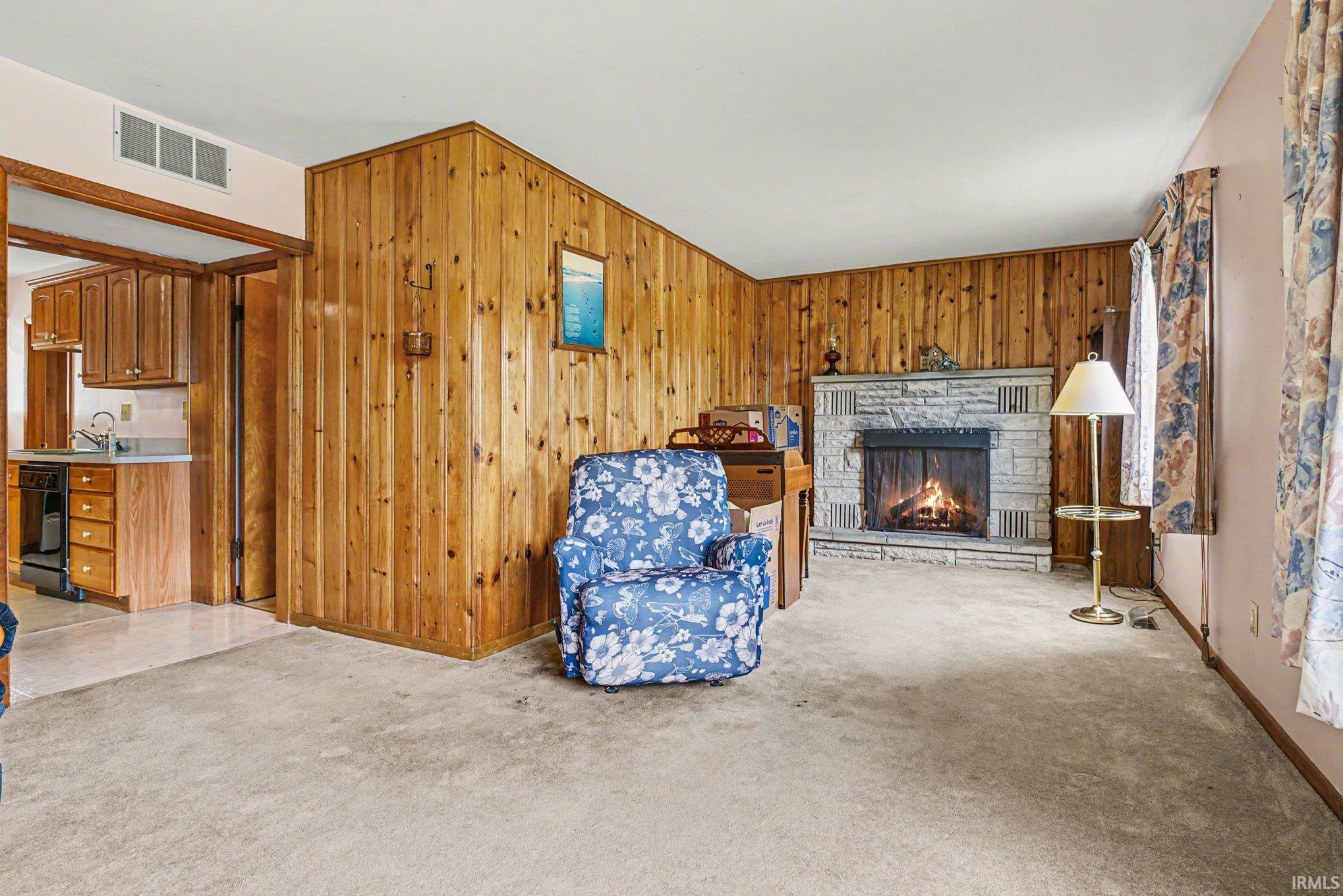 Living area featuring wood-paneled walls and a stone fireplace