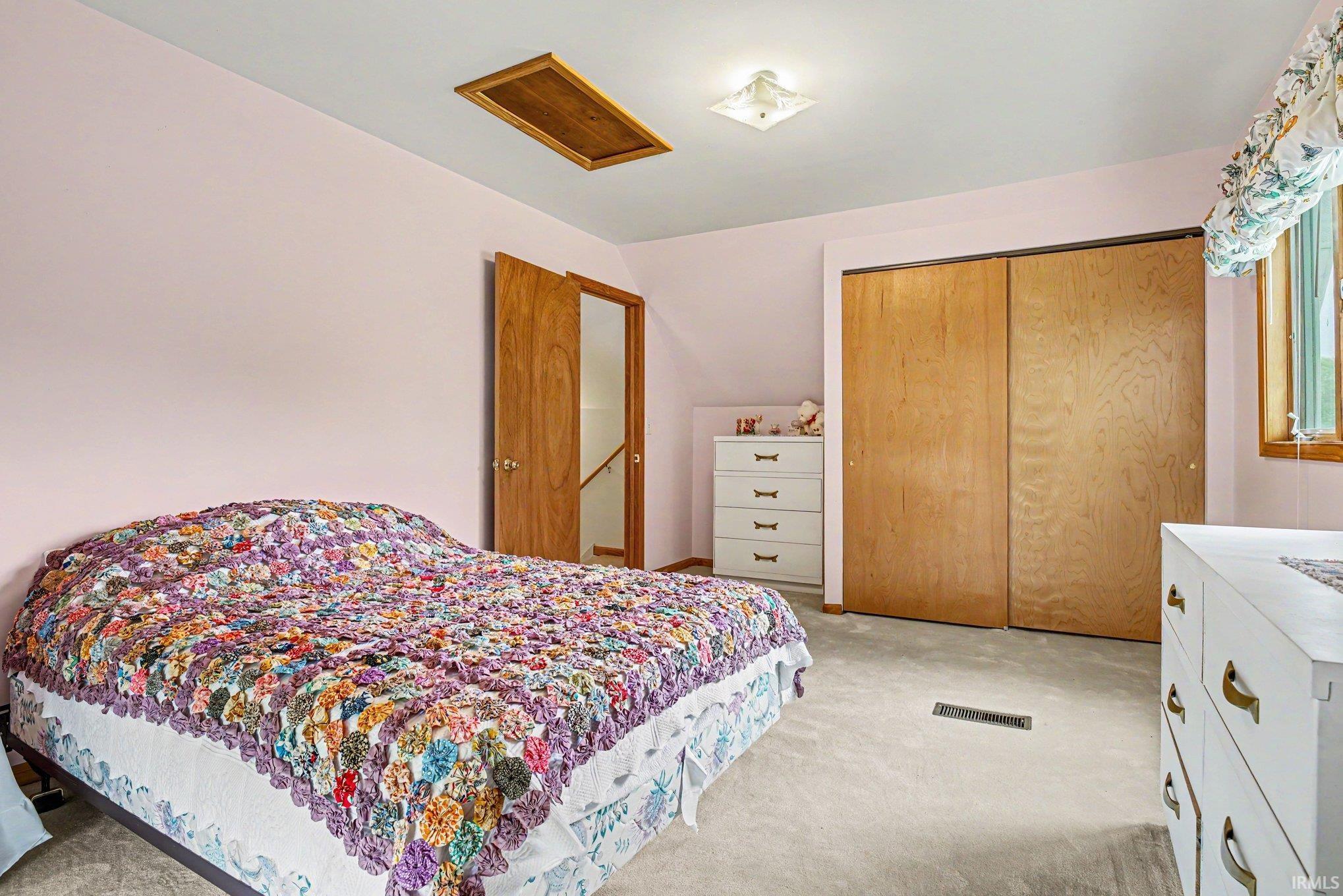 Carpeted interior space featuring a ceiling light fixture, a window with wood trim, and a wood-finish interior door