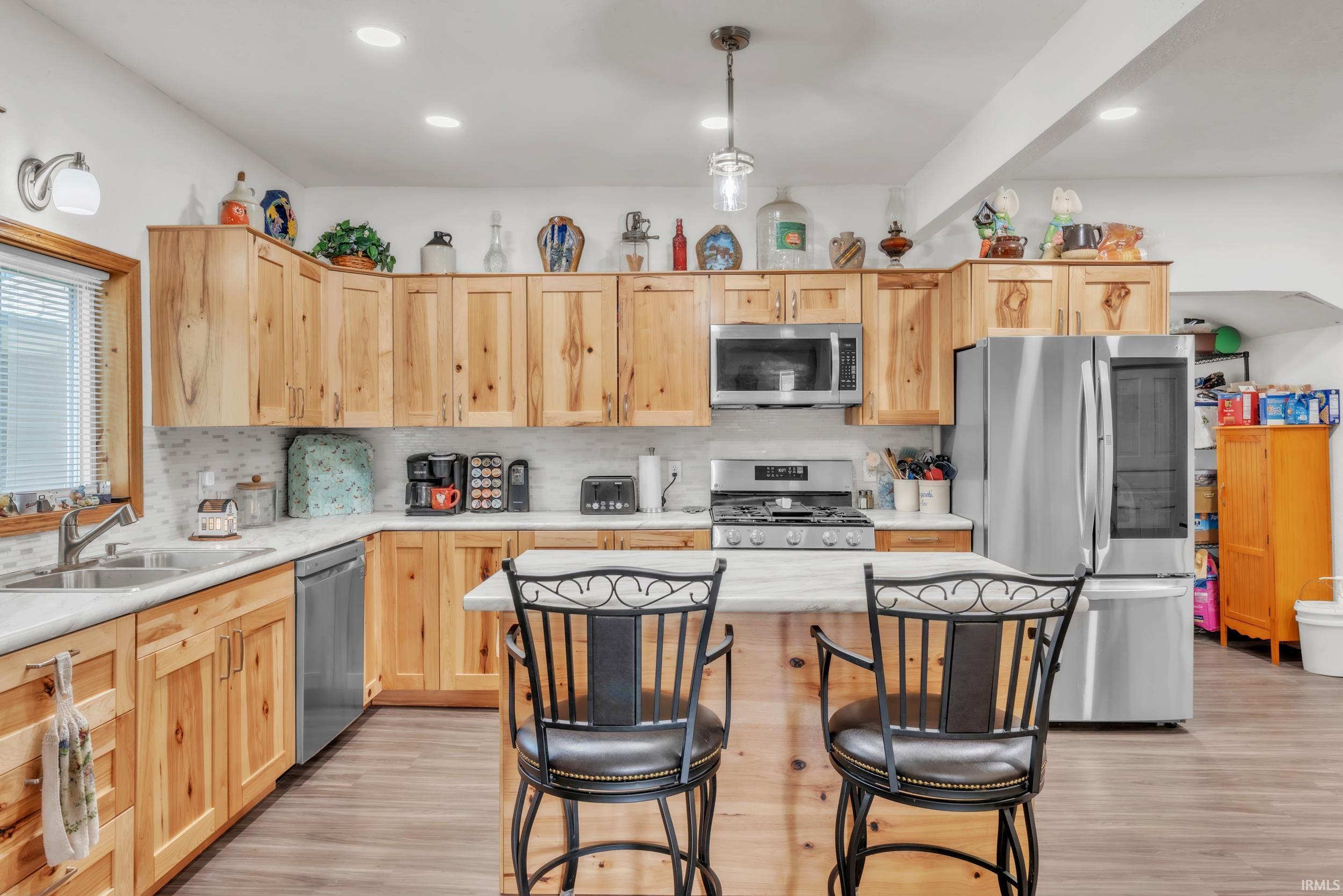 Kitchen featuring wood cabinetry, stainless steel appliances, white countertops, and a central island with seating