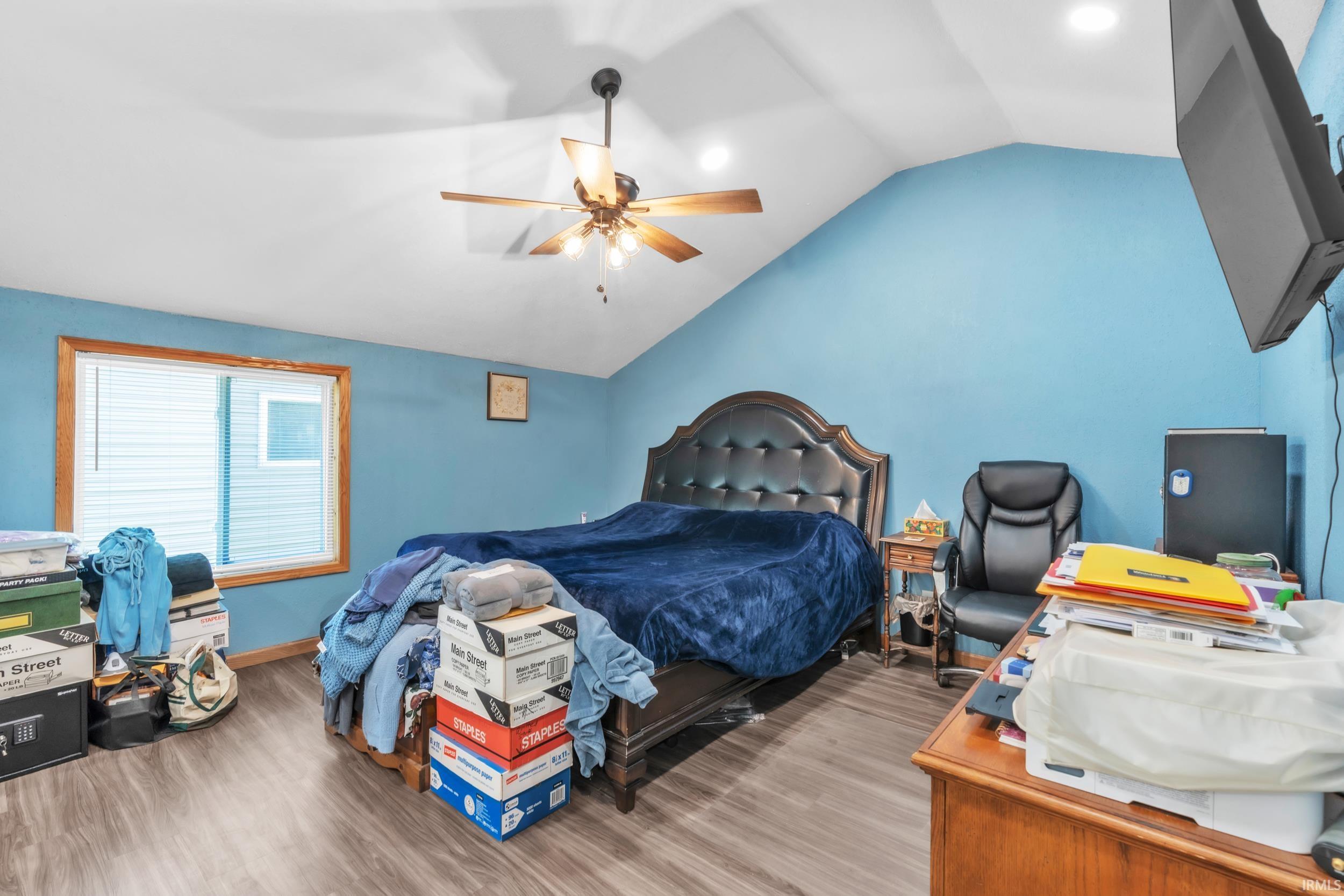 Room with vaulted ceiling, wood-finish flooring, and a ceiling fan with light fixture