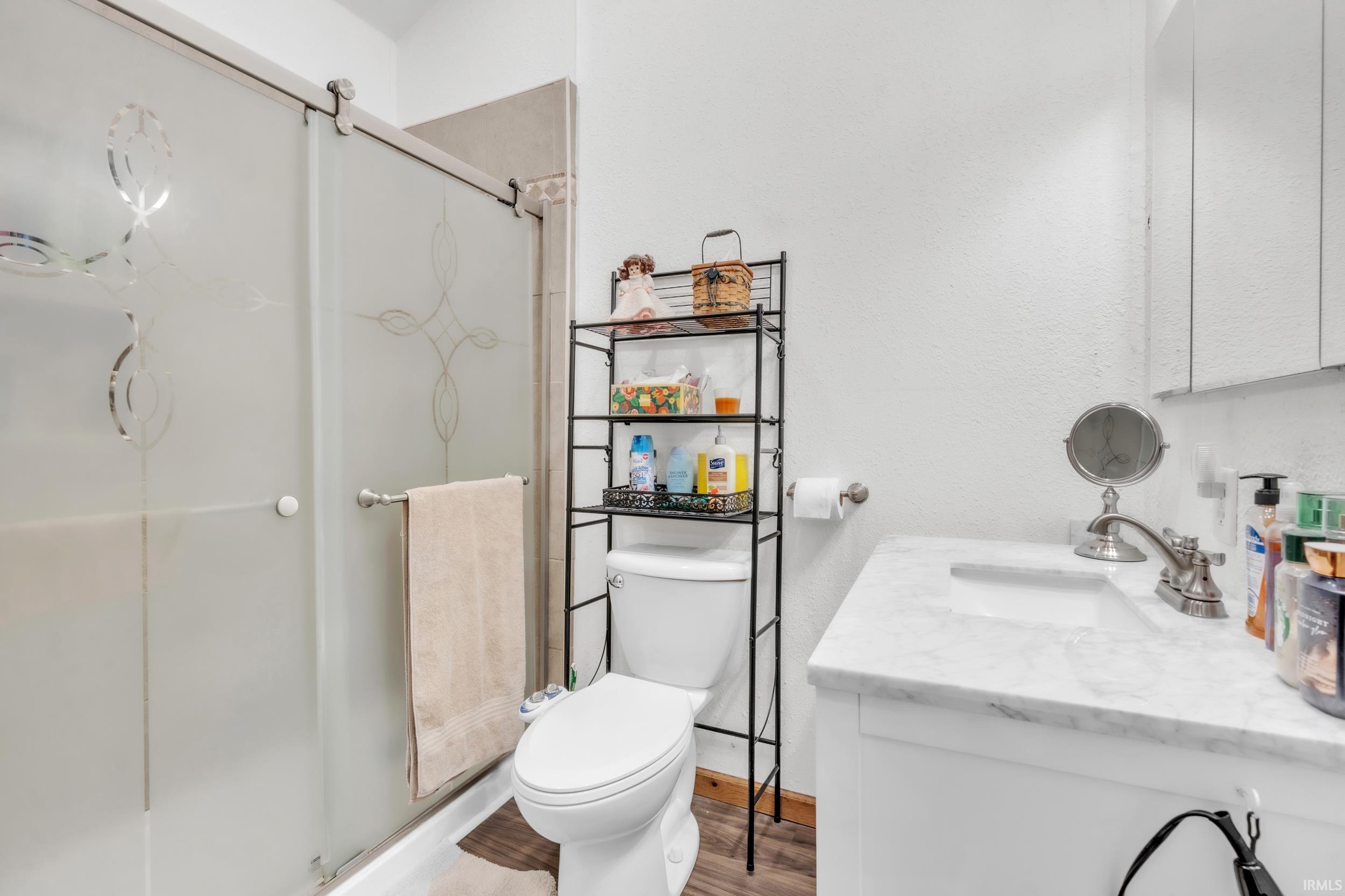 Bathroom featuring a shower with frosted glass doors, a white vanity with an integrated sink, and a white toilet
