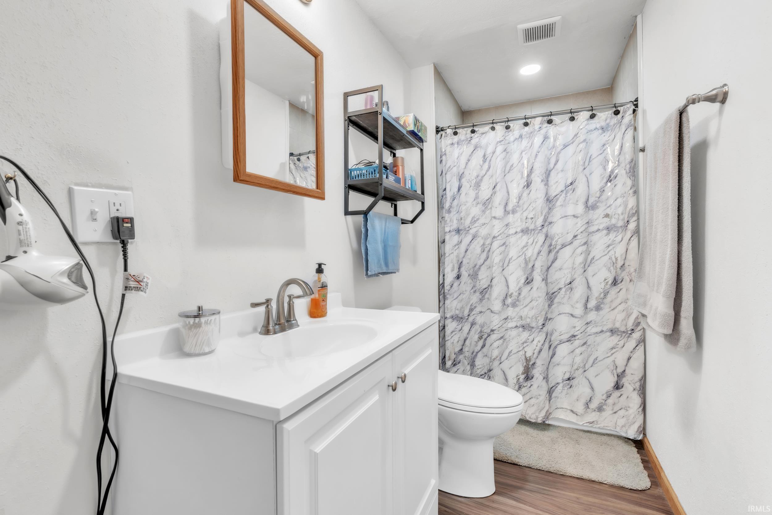Bathroom vanity featuring a white countertop with integrated sink and brushed nickel faucet