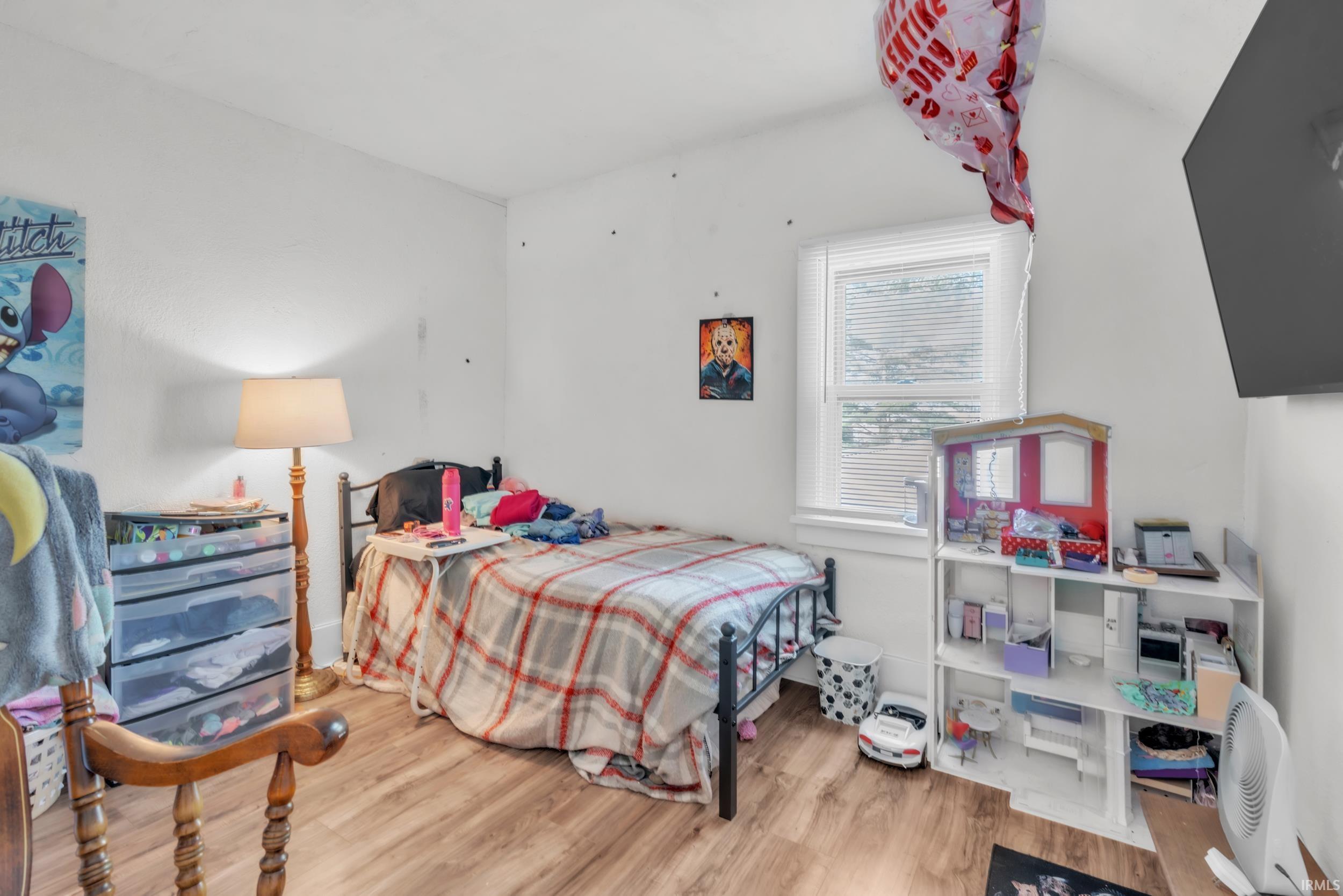 Bright room featuring wood-finish flooring, white walls, and a window with blinds