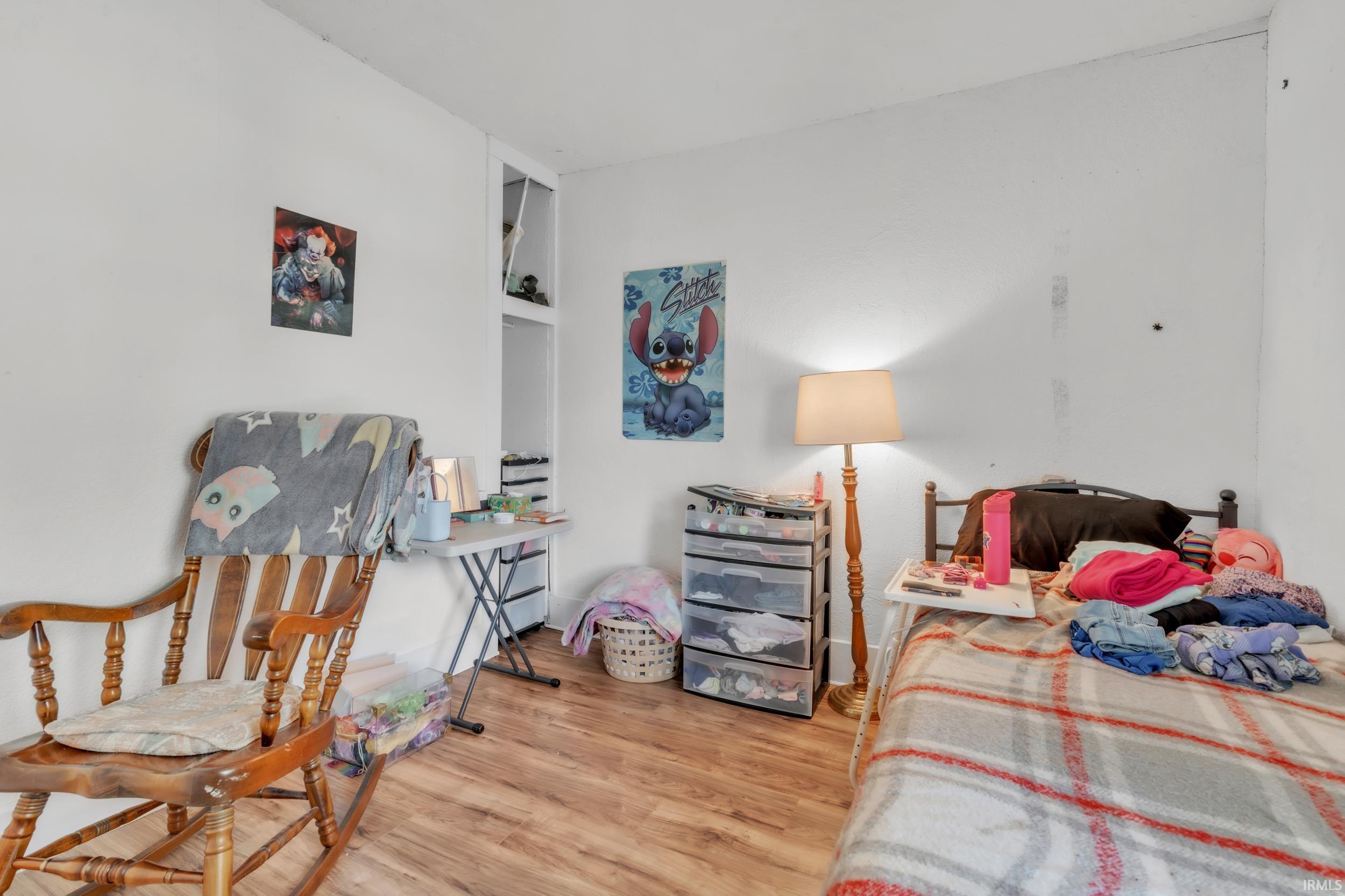 Room featuring wood-finish flooring, white painted walls, and built-in shelving
