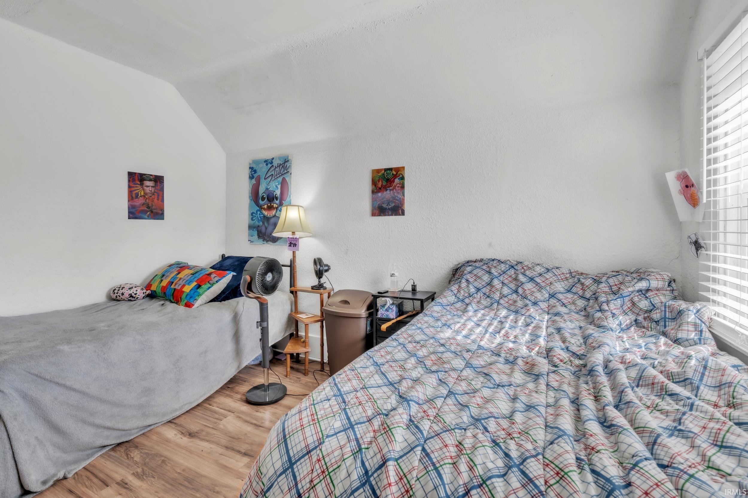 Room featuring wood-finish flooring, white walls, and a sloped ceiling