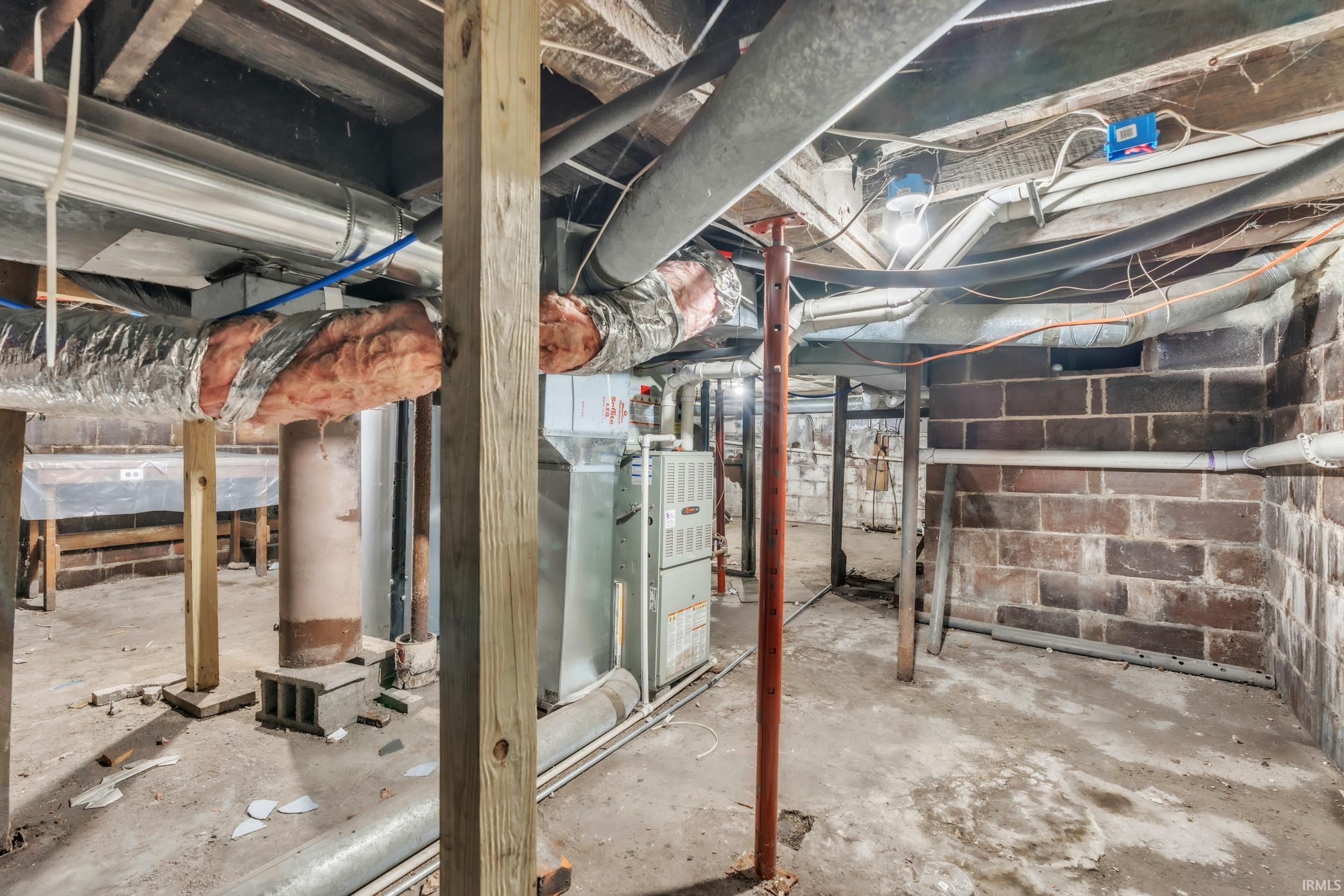 Unfinished basement featuring exposed brick foundation walls and concrete flooring