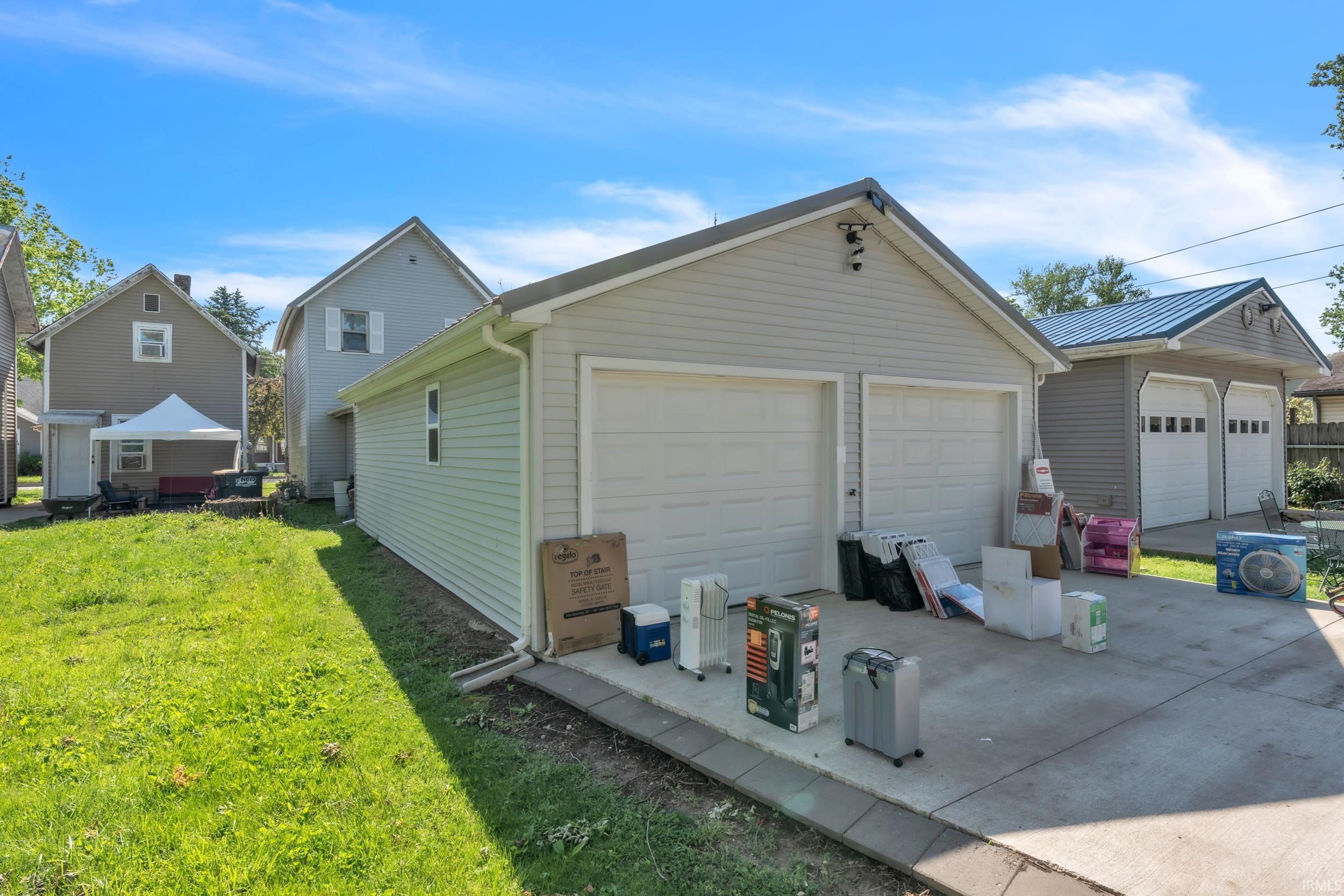 Detached garage featuring dual white panel garage doors, light-colored siding, and a dark-toned roof