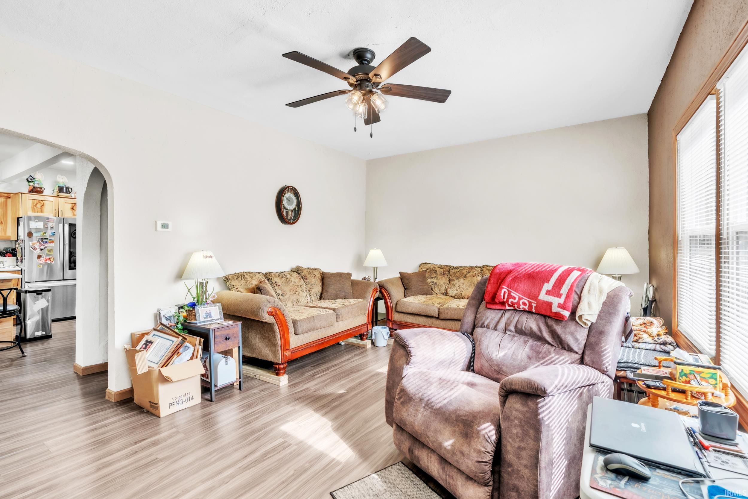 Living area featuring wood-finish flooring, a ceiling fan, and window blinds