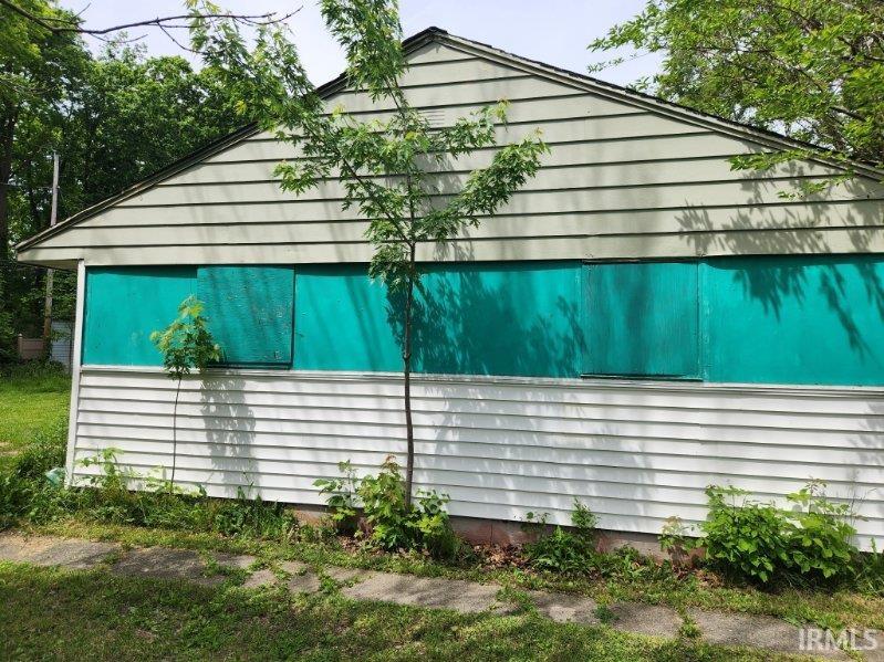 Gabled exterior featuring horizontal siding and boarded window openings