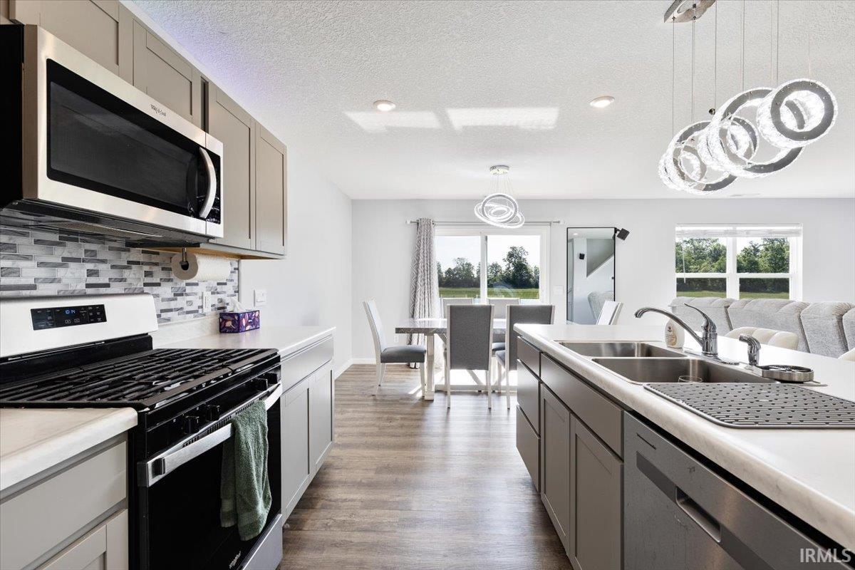 Modern kitchen featuring light gray cabinetry, stainless steel appliances, and a mosaic tile backsplash