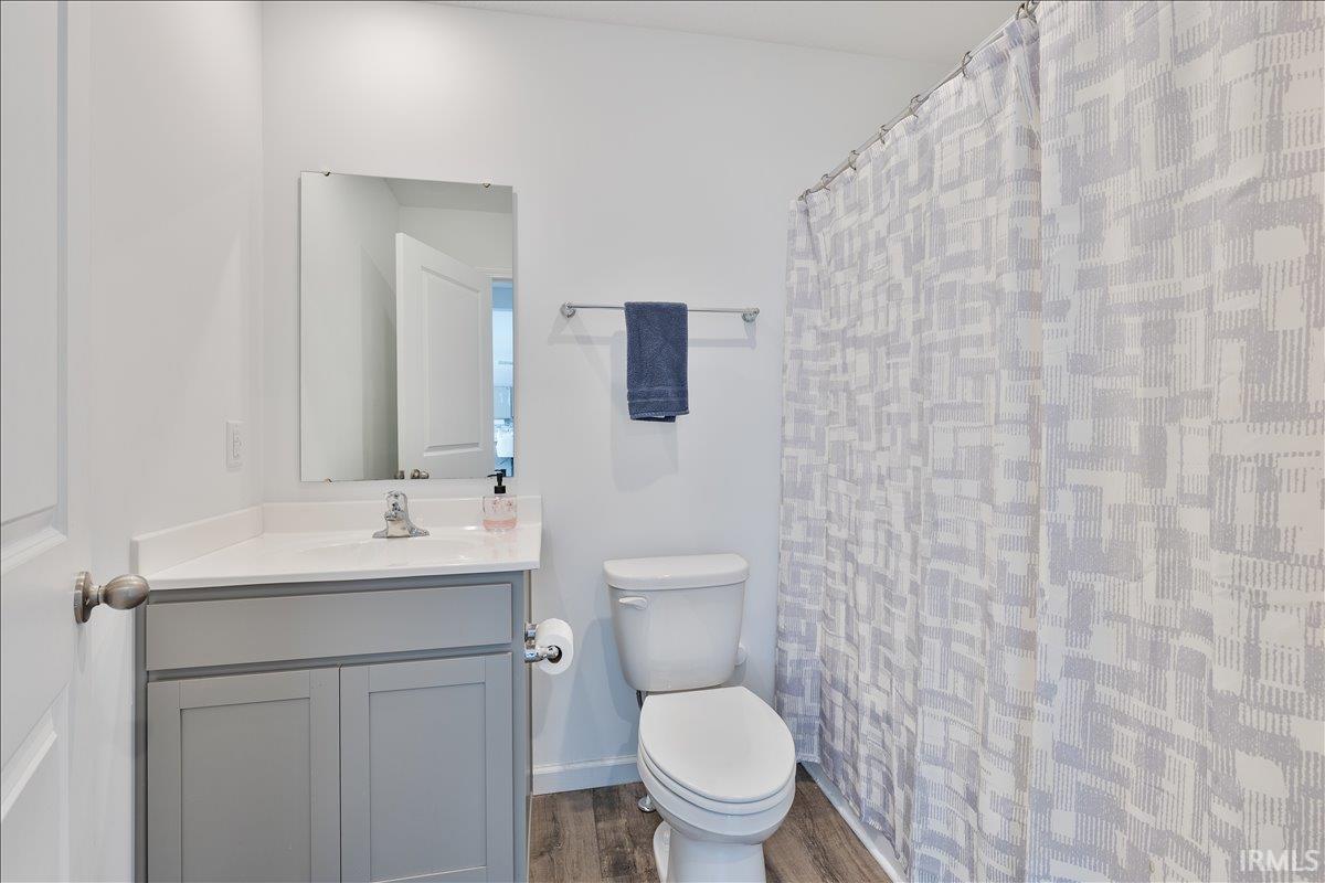 Contemporary bathroom featuring a light gray vanity with a white countertop, a rectangular mirror, and wood-finish flooring