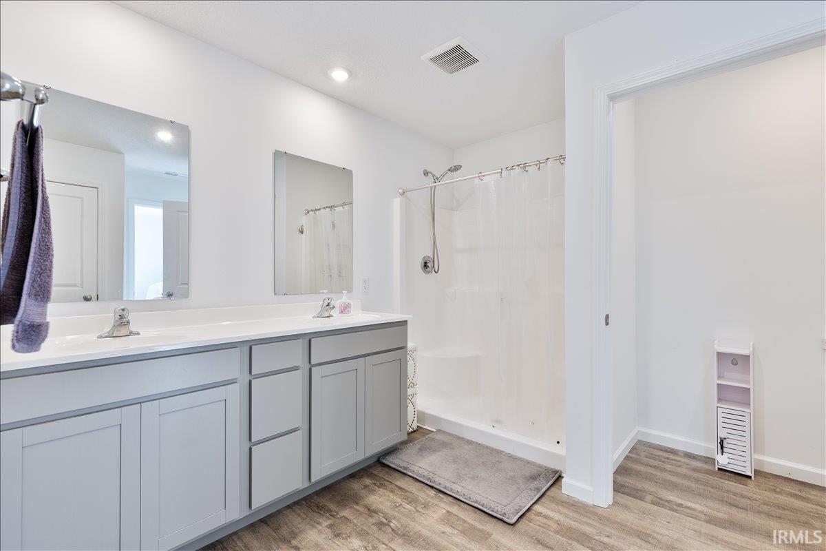 Dual sink vanity featuring gray cabinetry, white countertops, and chrome fixtures