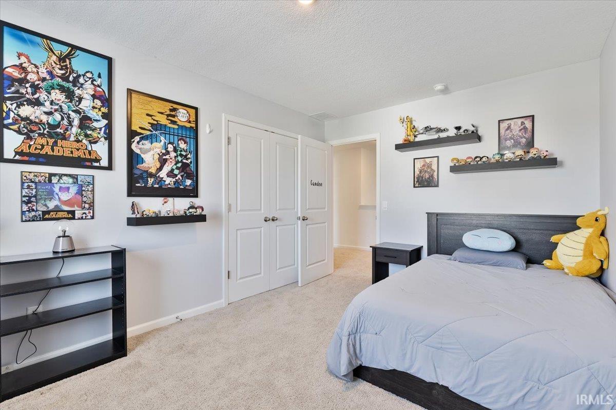 Carpeted bedroom featuring white walls, a built-in closet with double doors, and multiple floating shelves