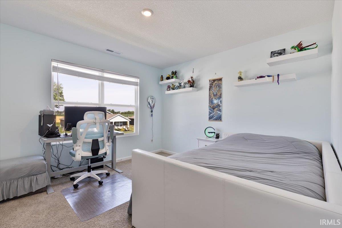 Carpeted bedroom featuring a large window with blinds, recessed lighting, and multiple wall-mounted floating shelves