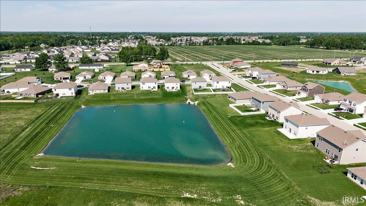 Aerial perspective of a residential development featuring a central retention pond