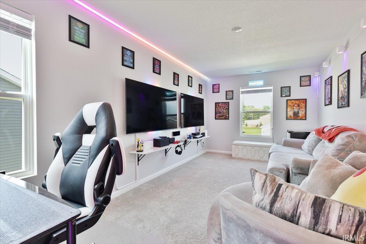 Carpeted room featuring multiple windows, recessed ceiling lighting, and wall-mounted shelving