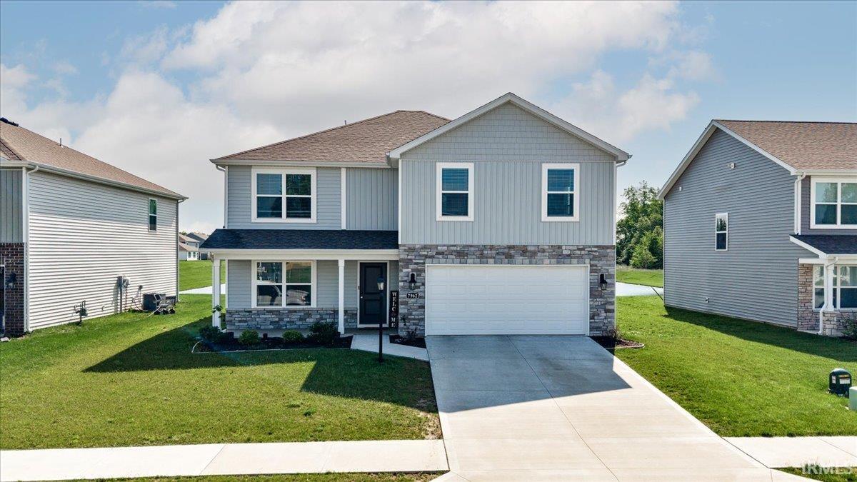 Two-story residence featuring light gray siding, a stone facade, and a covered front porch with white columns