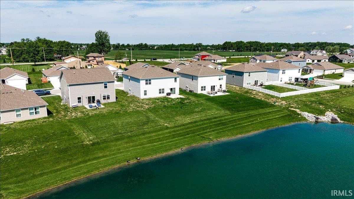 Rear exterior featuring a patio, sliding glass door, and a manicured lawn overlooking the water