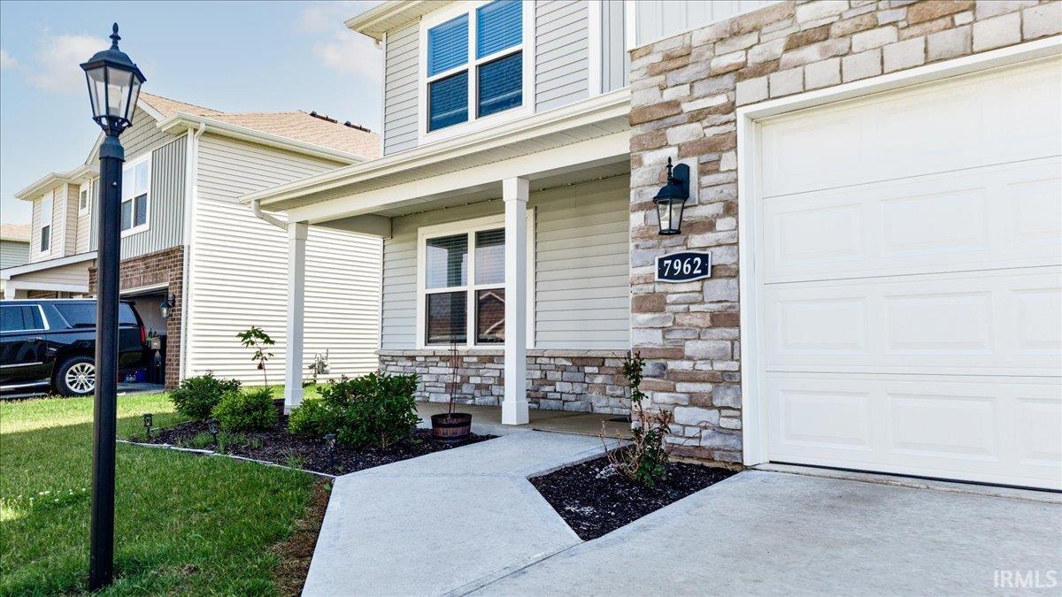 Welcoming front exterior featuring a covered porch, stone veneer accents, and a concrete walkway