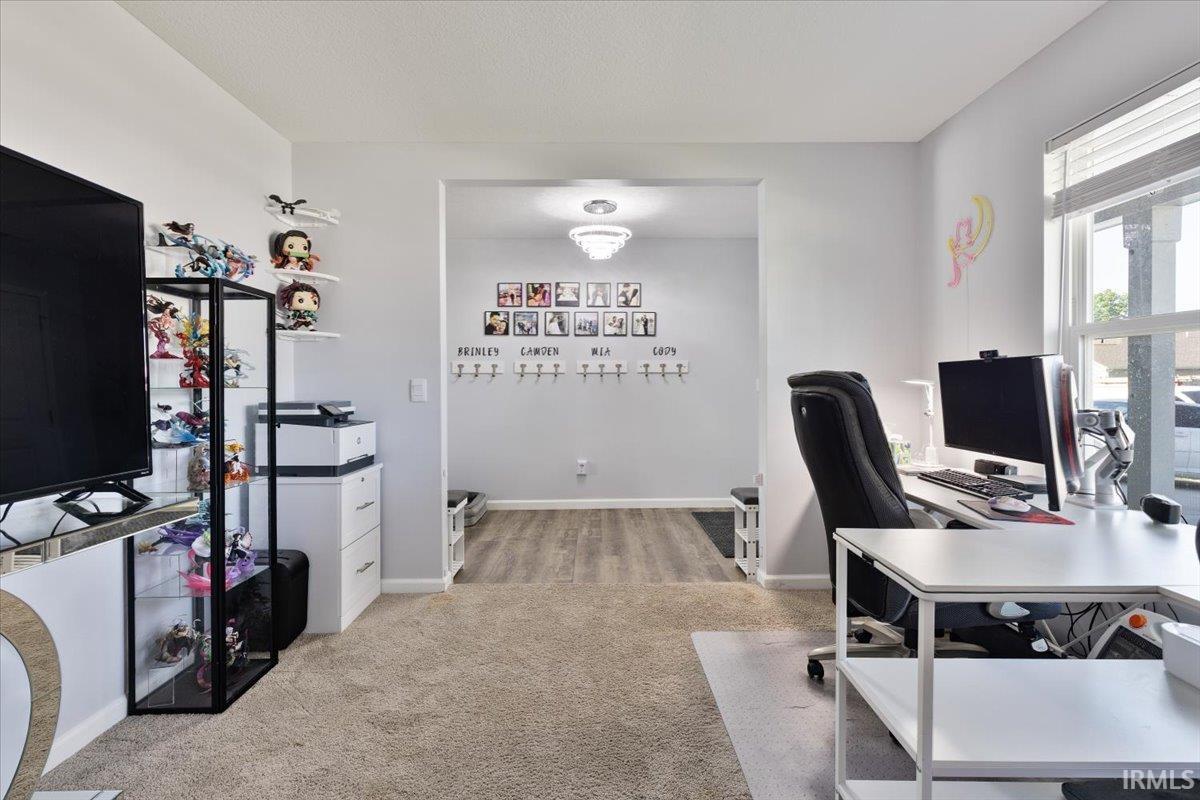Versatile interior space featuring light gray walls, carpet flooring, and a large window with horizontal blinds