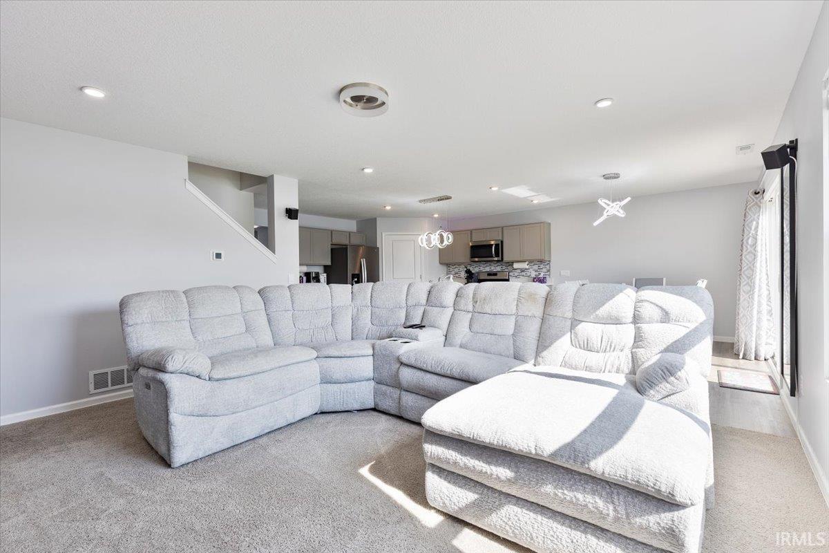 Spacious living area featuring neutral carpeting, light gray walls, and recessed lighting