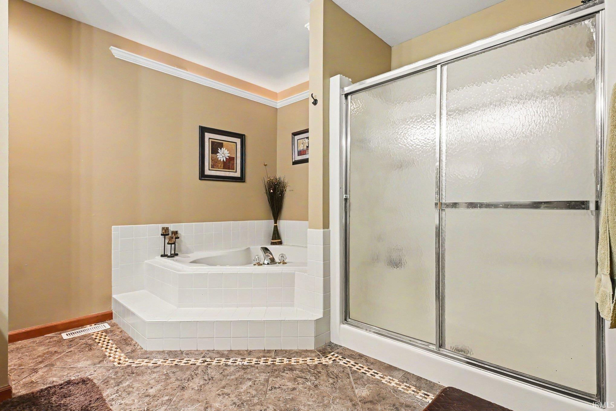 Built-in corner soaking tub with white tile surround, adjacent to a shower with textured glass sliding doors