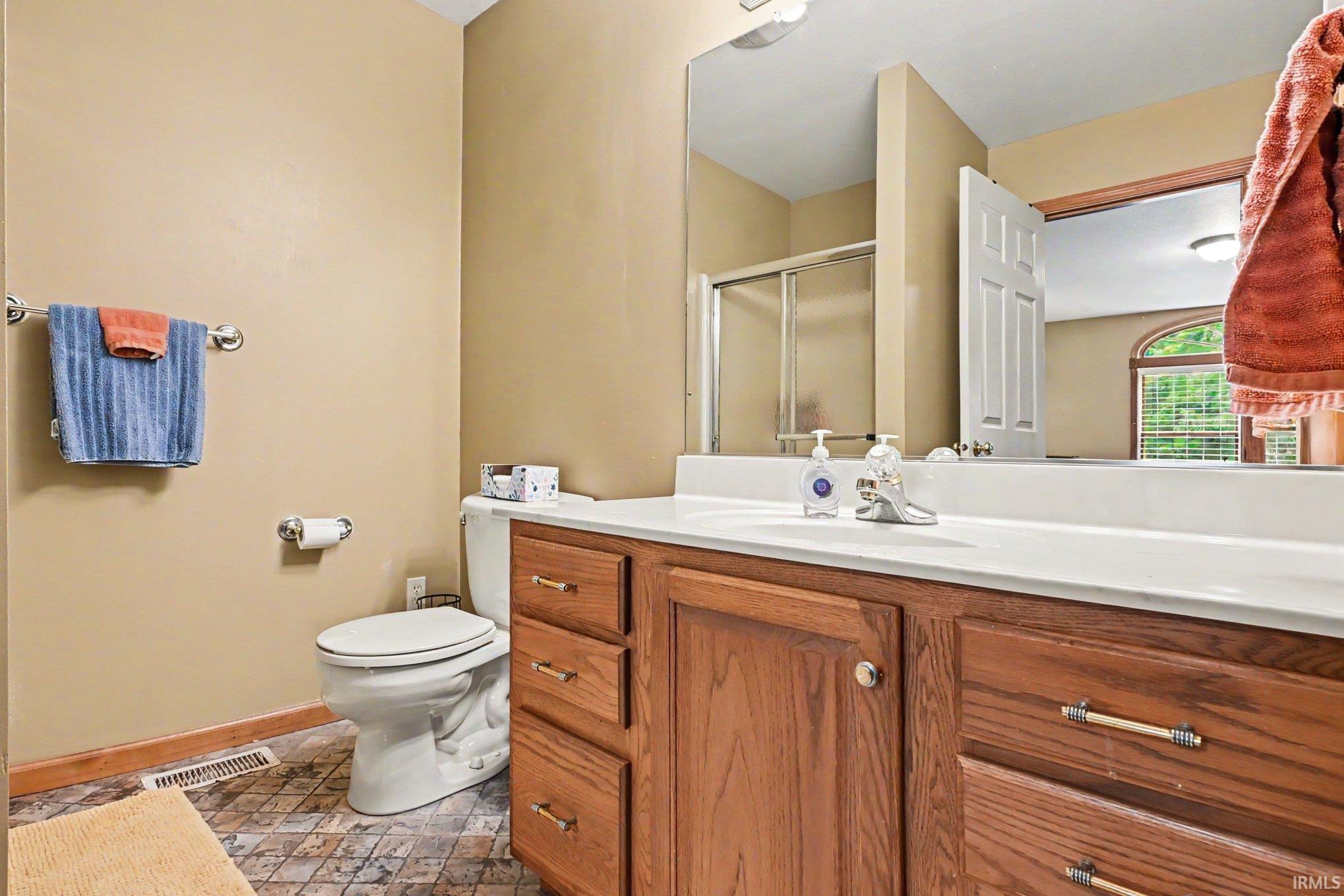 Bathroom vanity featuring wood-finish cabinetry, a white countertop, and an integrated sink