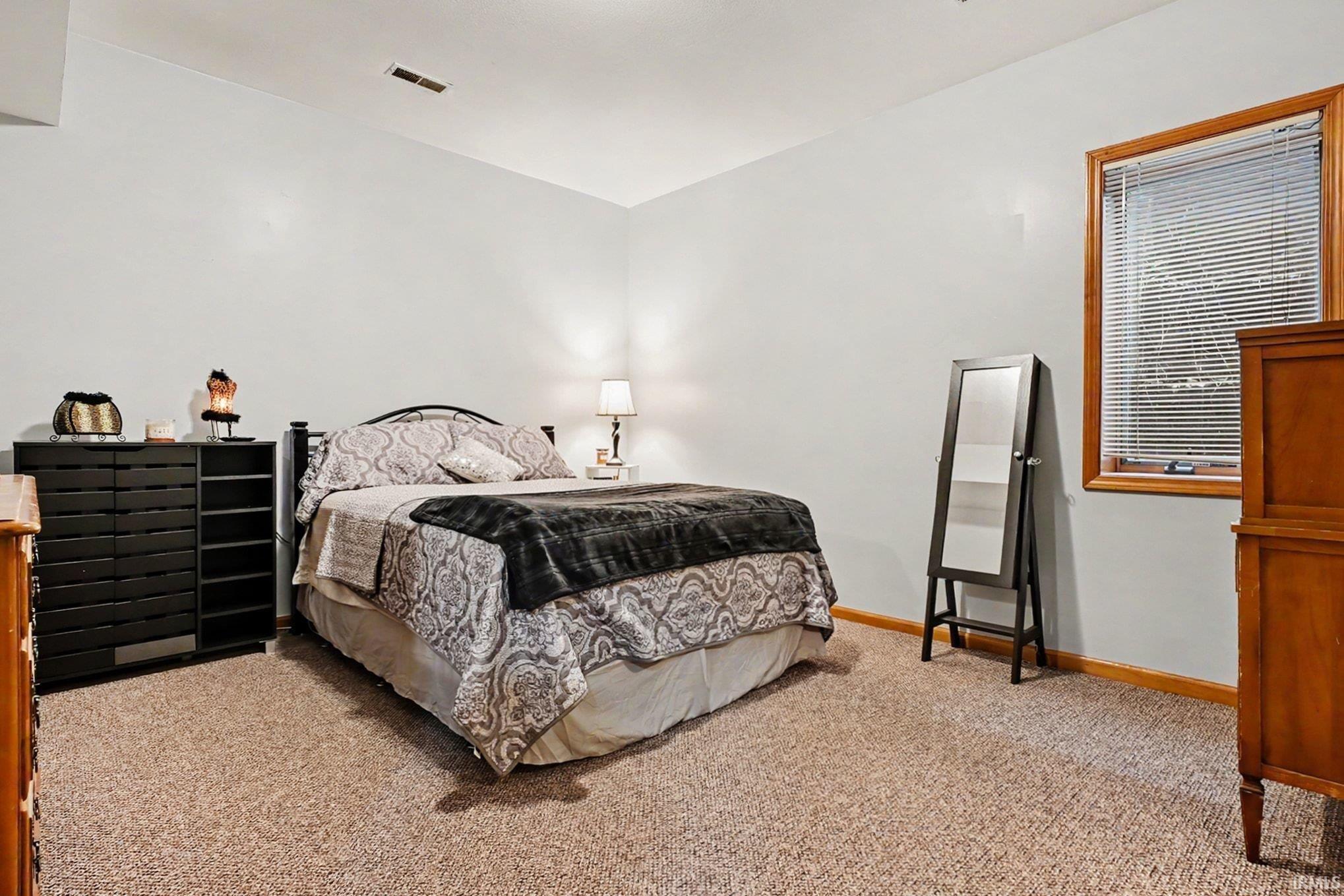 Carpeted room with light neutral walls, a window featuring wood trim, and a ceiling-mounted light fixture