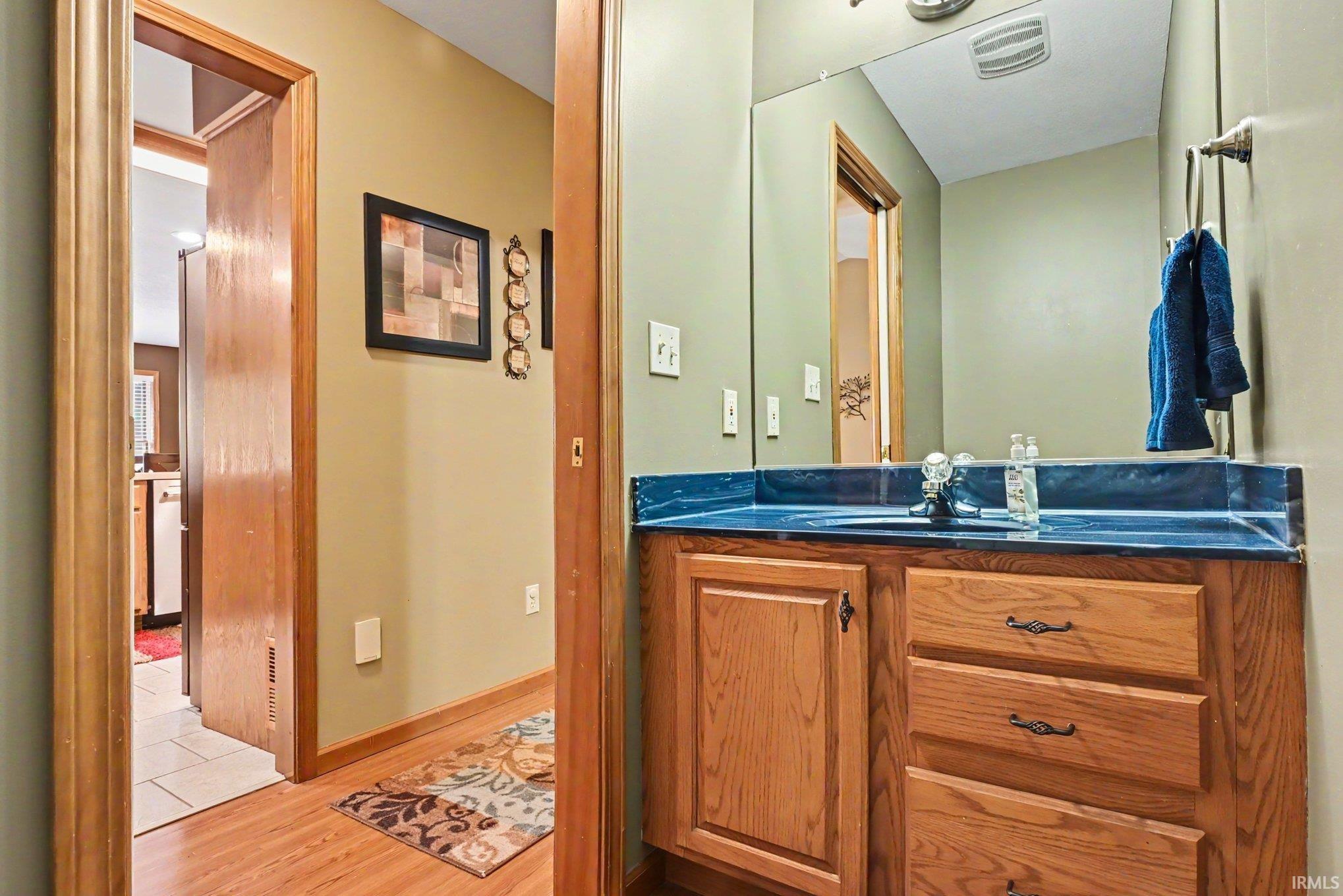 Bathroom vanity featuring wood-finish cabinetry and a blue countertop with an integrated sink