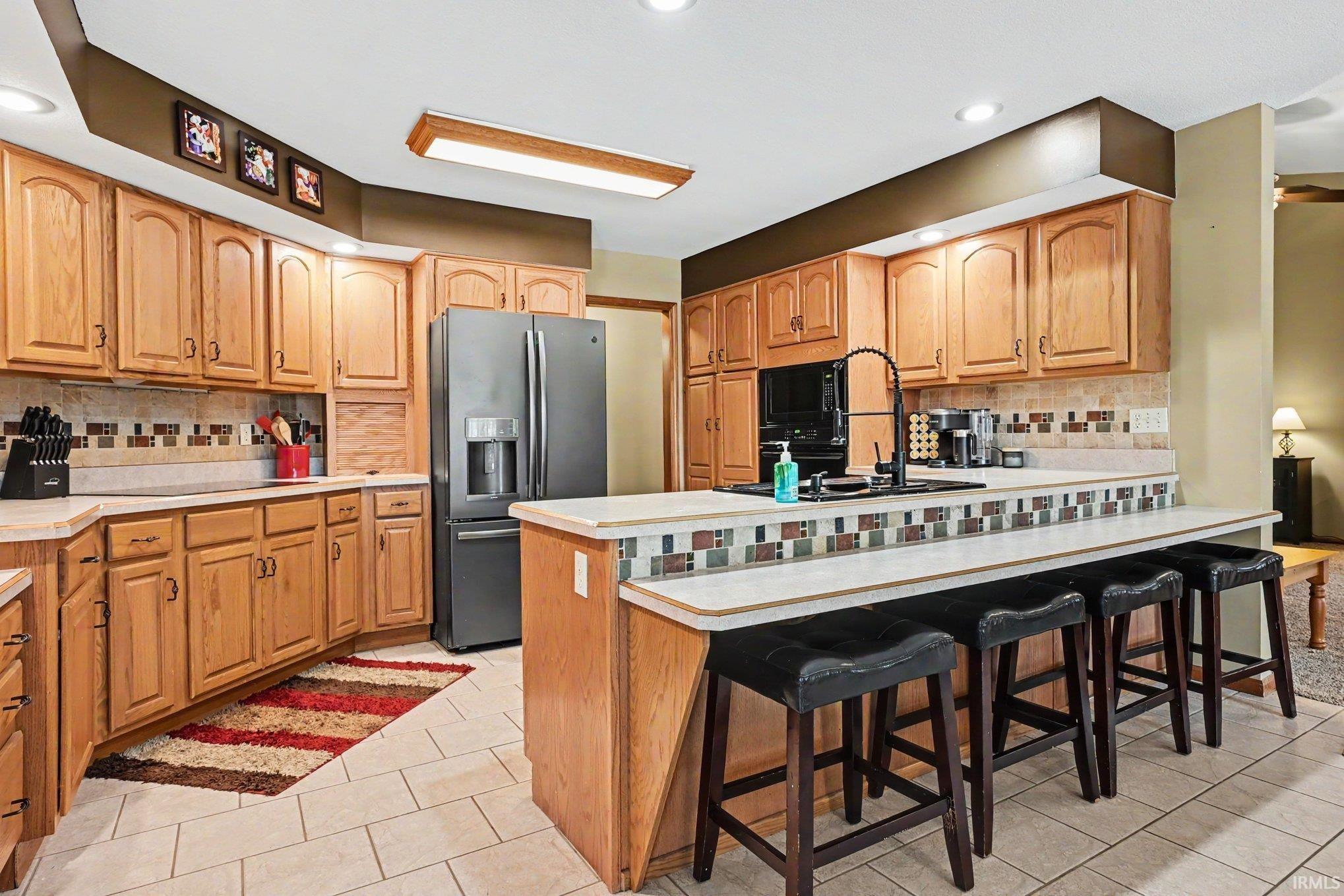 Kitchen featuring wood cabinetry, stone-finish countertops, tiled backsplash, and recessed lighting