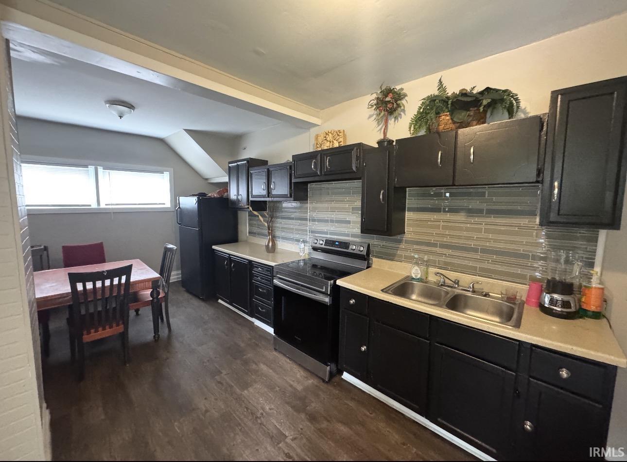 Kitchen featuring black cabinetry, light countertops, and a subway tile backsplash