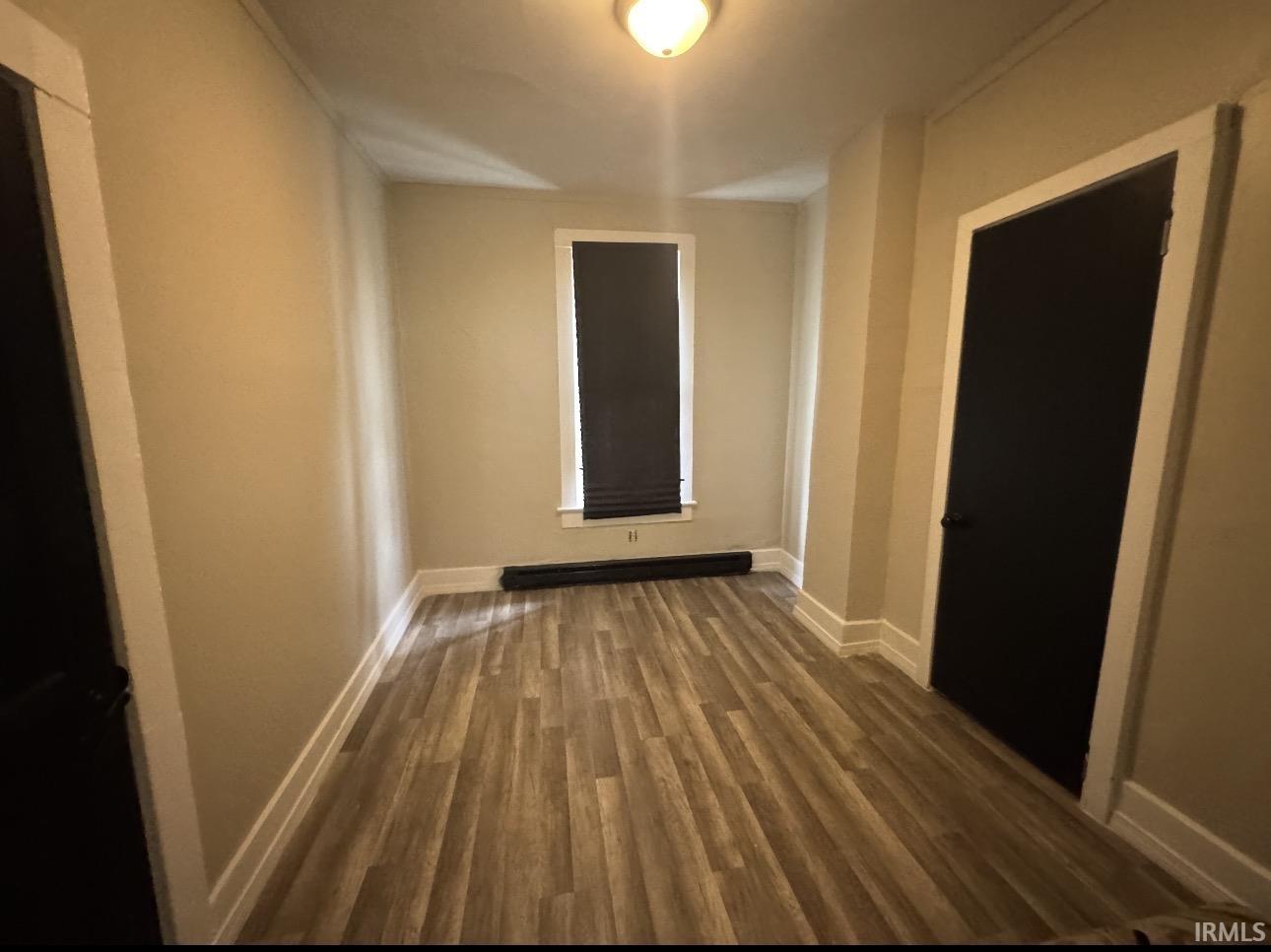 Room featuring wood-finish flooring, neutral wall tones, and white baseboards