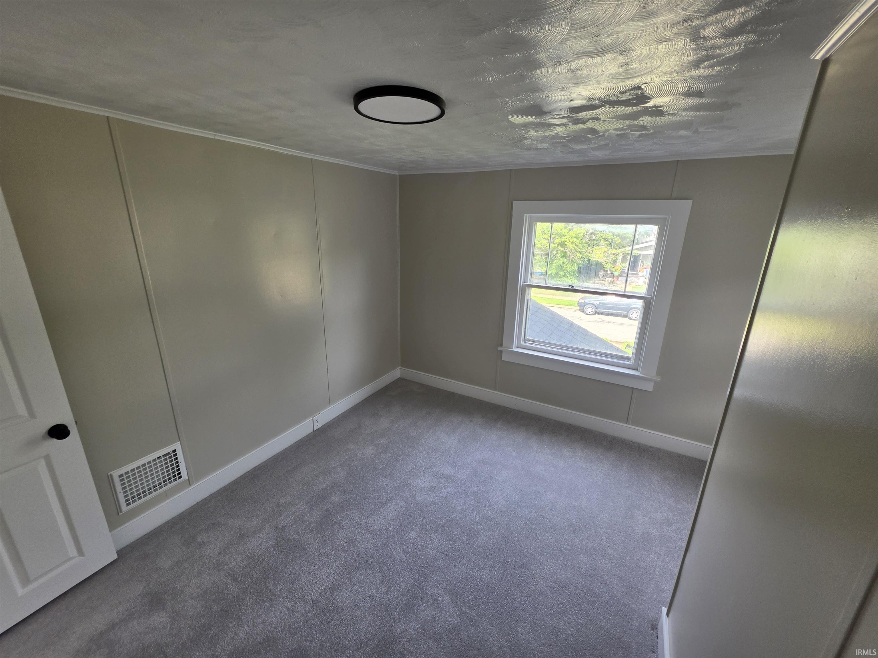 Room featuring neutral wall paneling, light gray carpeting, and white trim