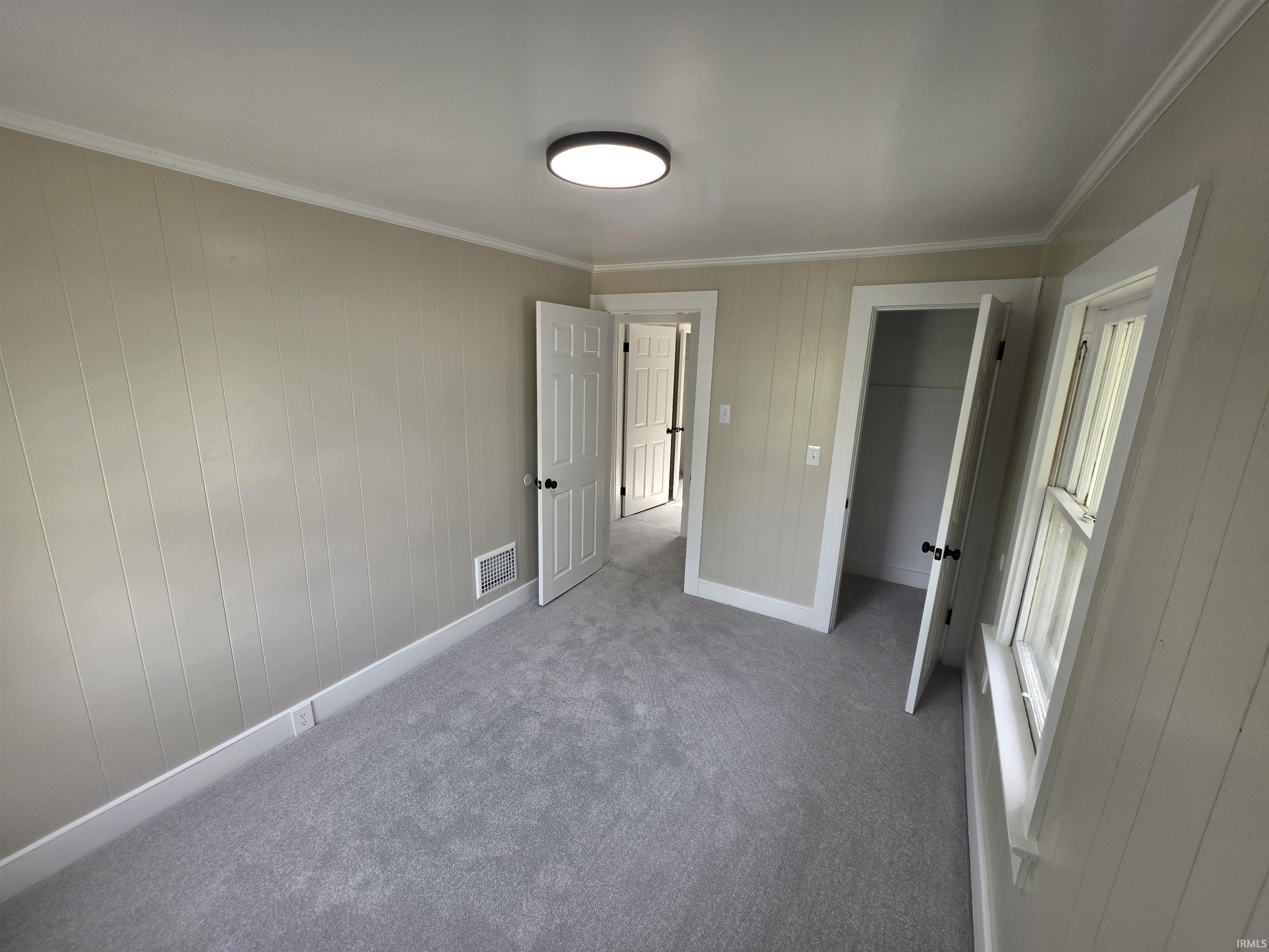 Room featuring light gray wall paneling and a contrasting white ceiling