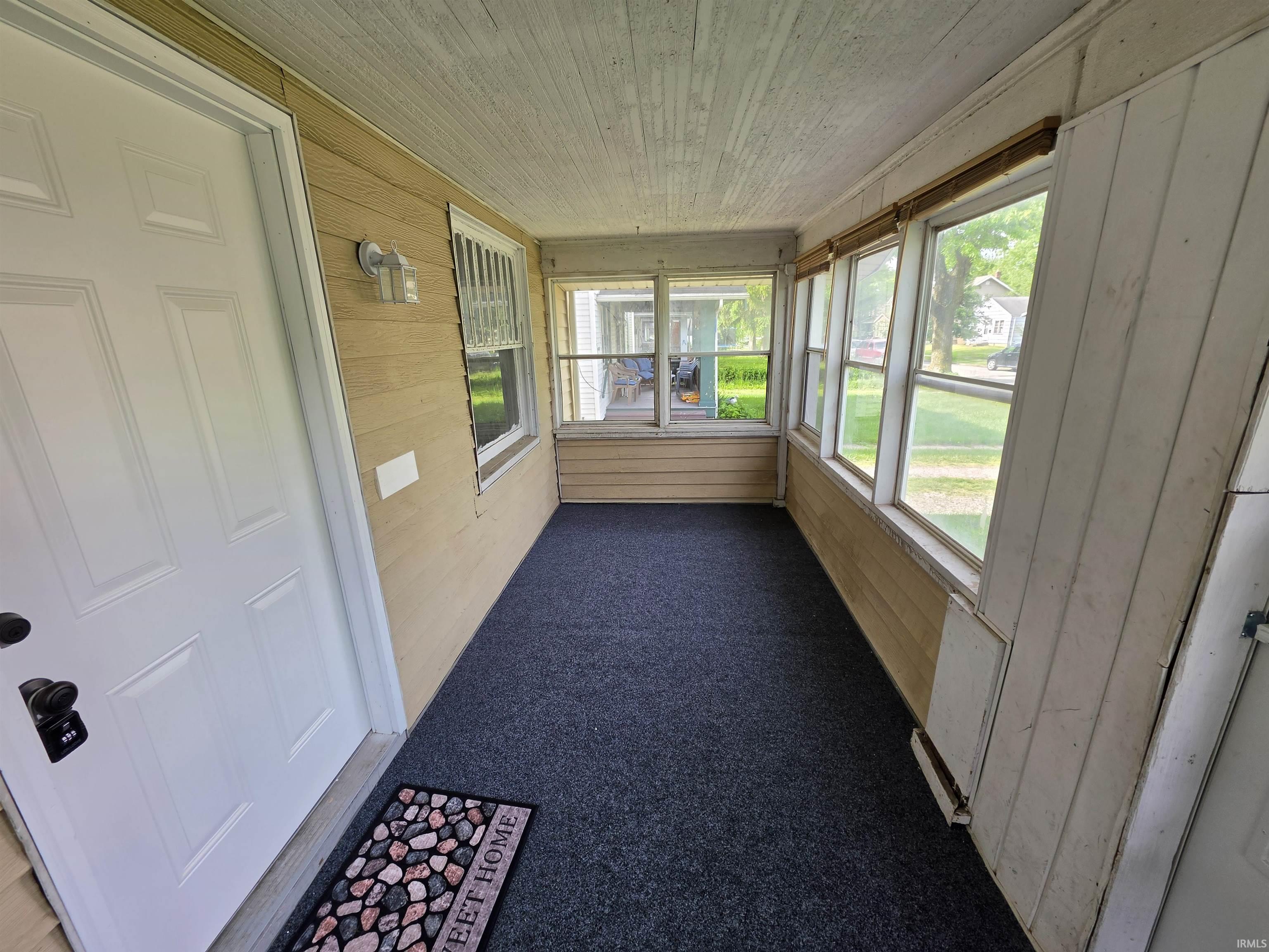 Enclosed porch featuring multiple windows, paneled walls, and textured ceiling