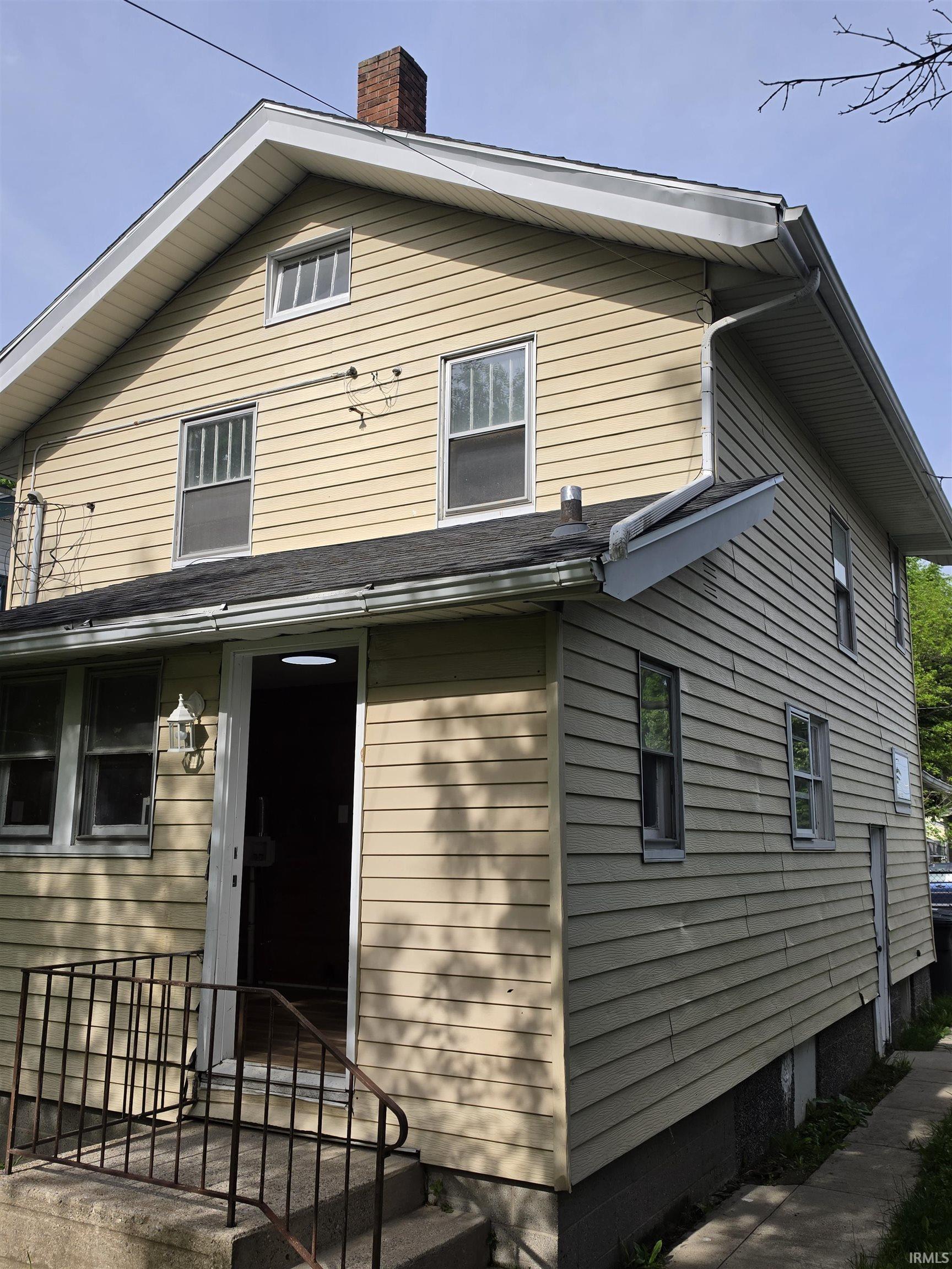 Two-story residence featuring light-toned horizontal siding, a gabled roofline, and multiple windows