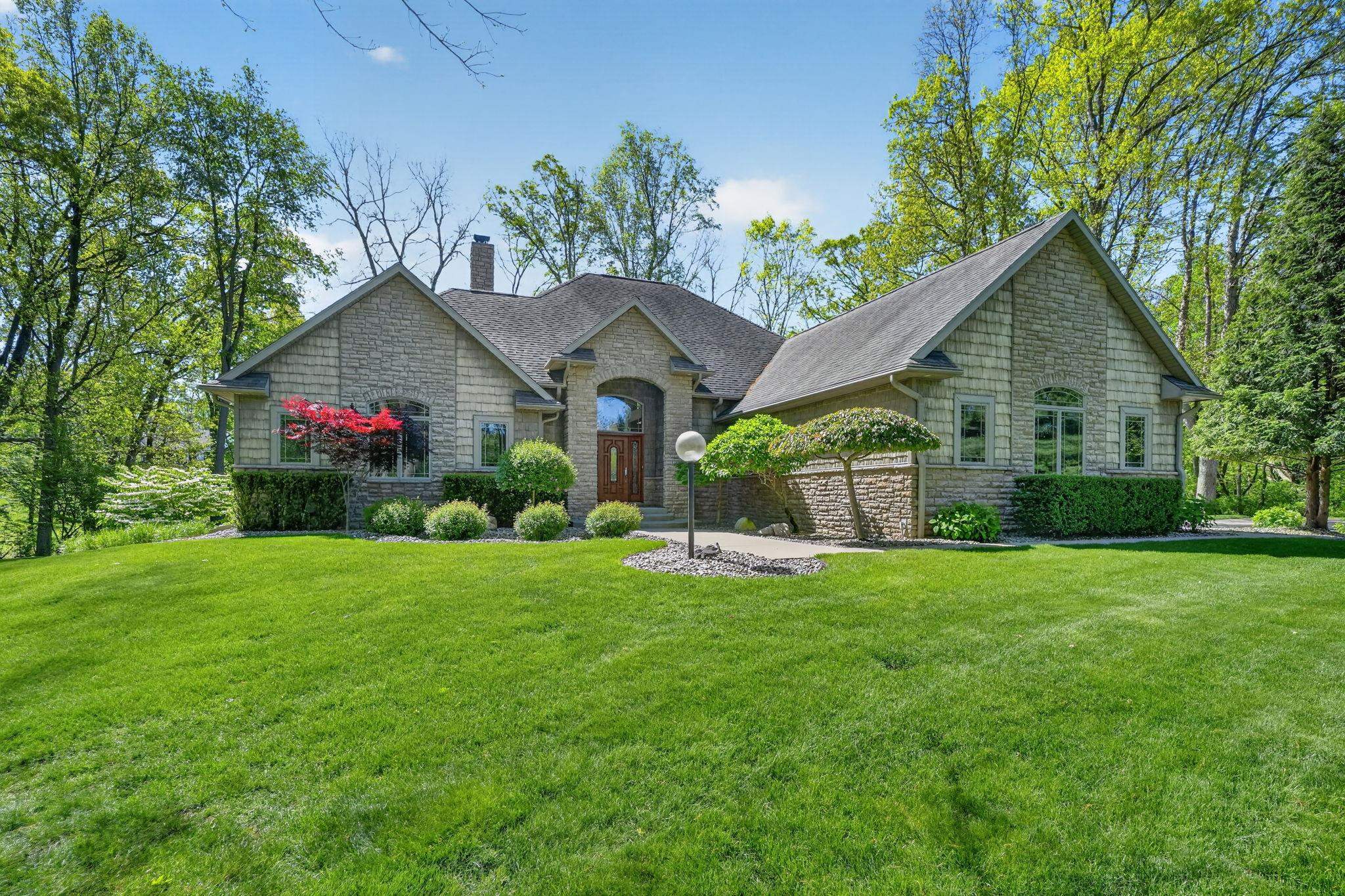 Stone veneer exterior featuring an arched entryway with a wood-finish double door
