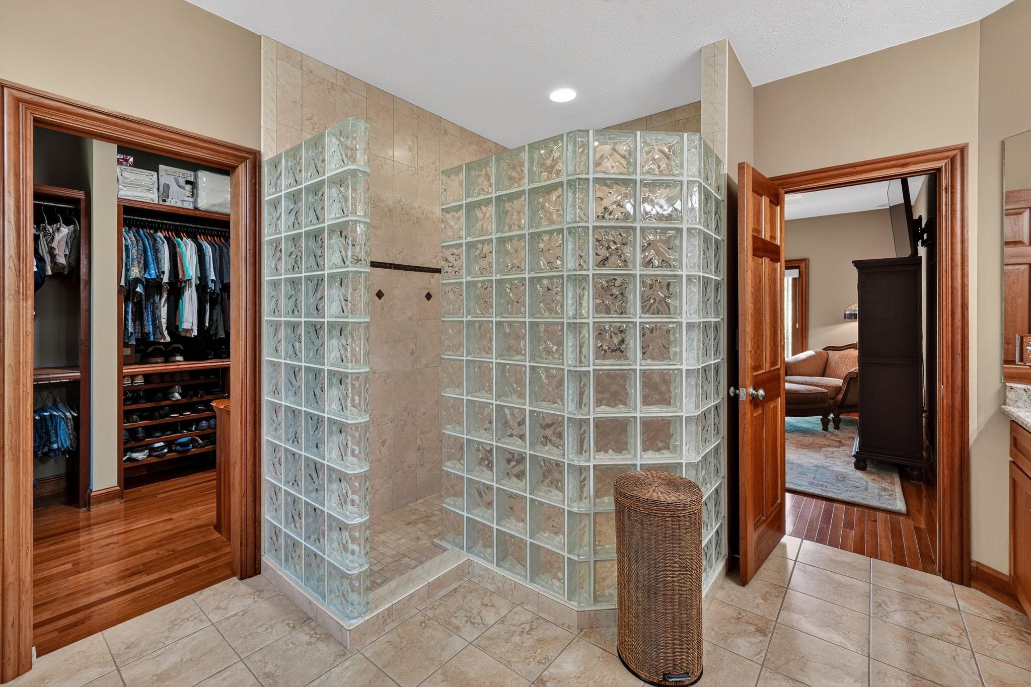 Spacious shower enclosure featuring glass block walls and light-toned tile