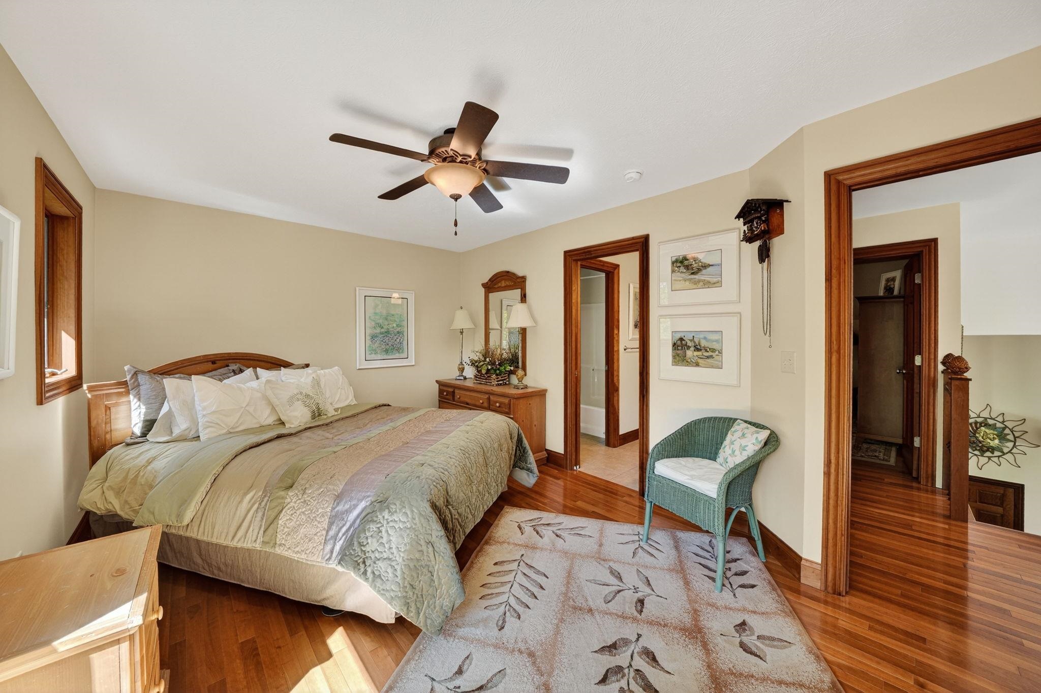 Hardwood flooring throughout featuring a ceiling fan, recessed window, and solid wood trim