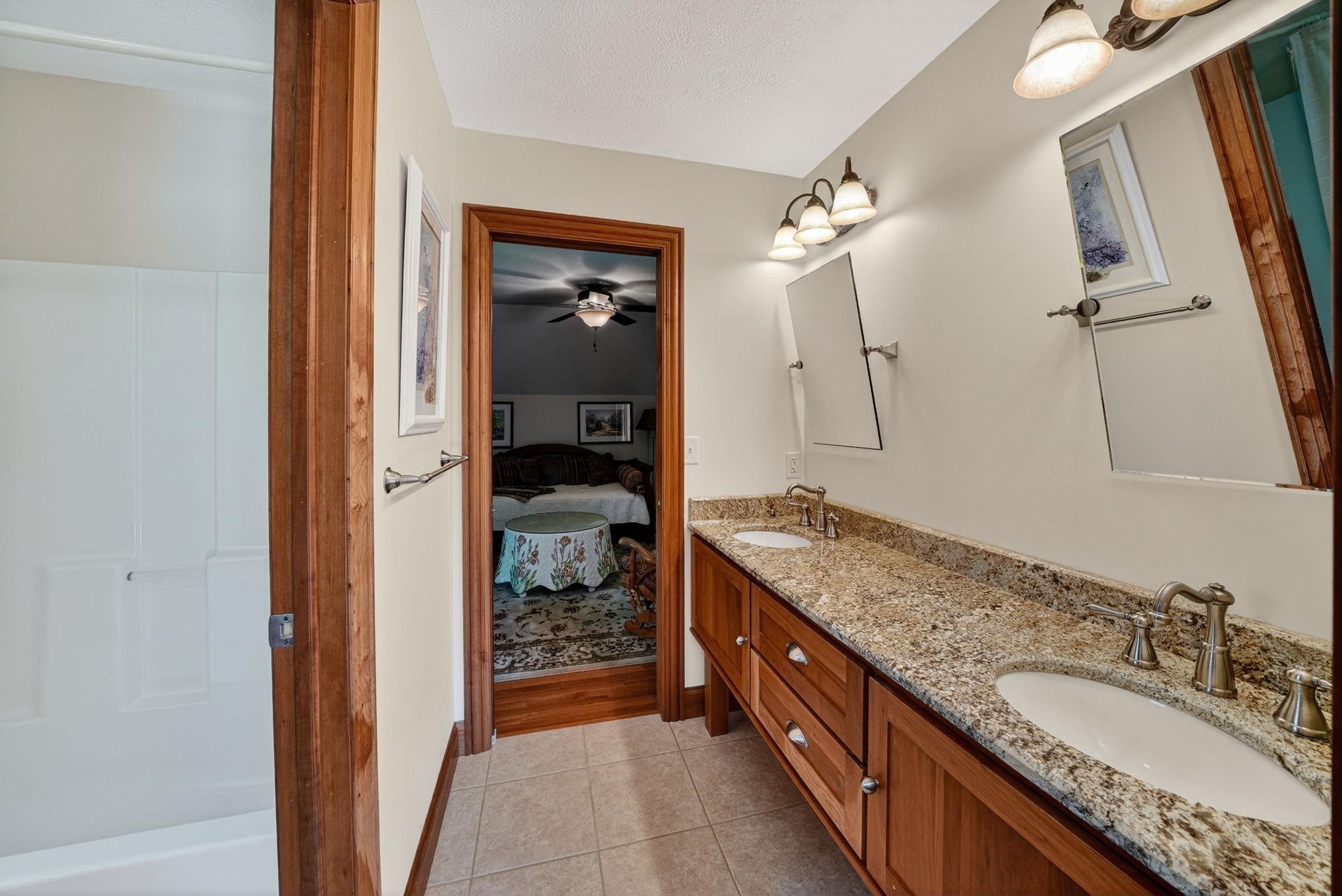 Bathroom featuring a dual vanity with a patterned countertop, integrated sinks, and individual mirrors