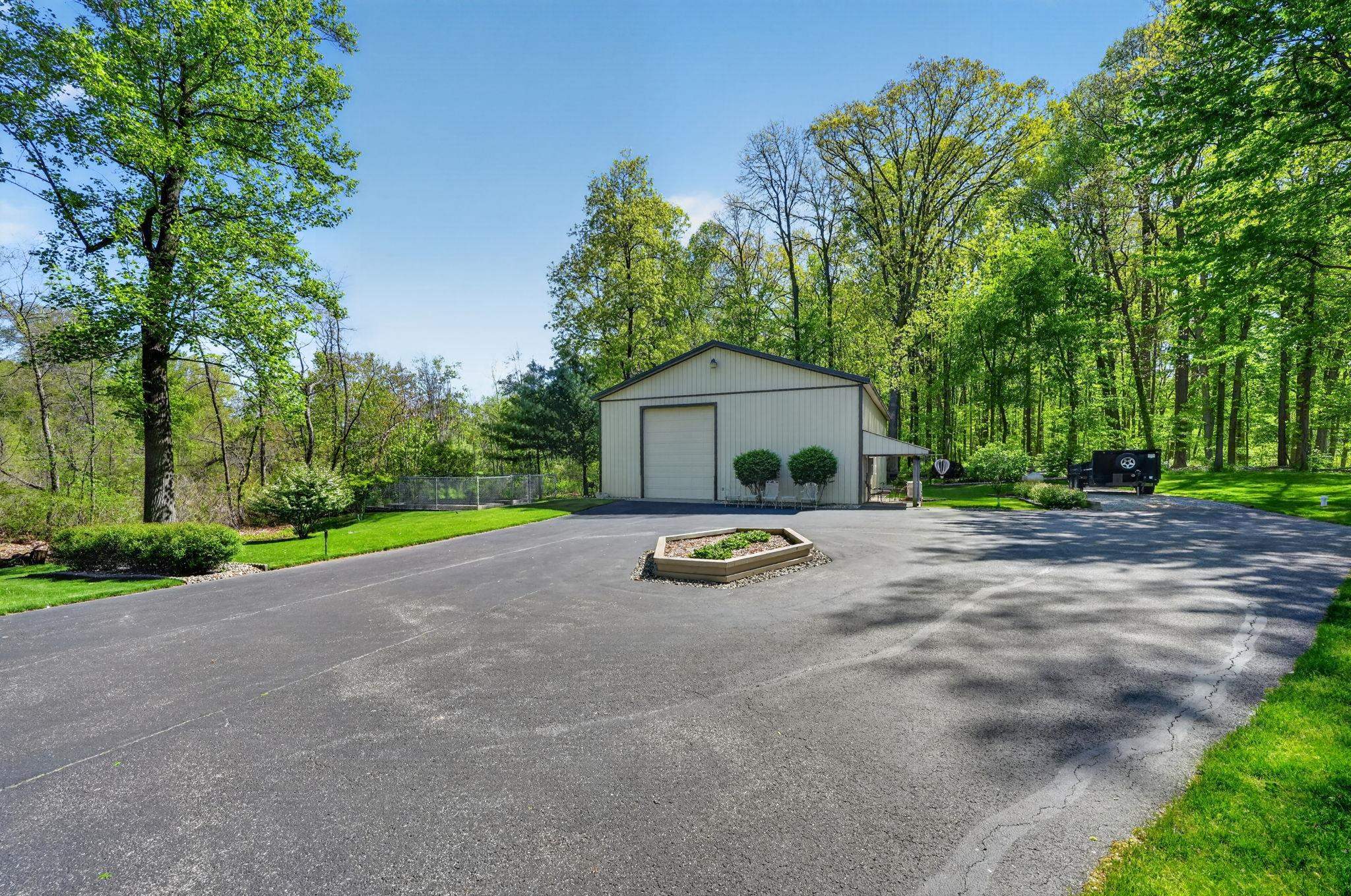 Large asphalt driveway leading to a detached workshop building