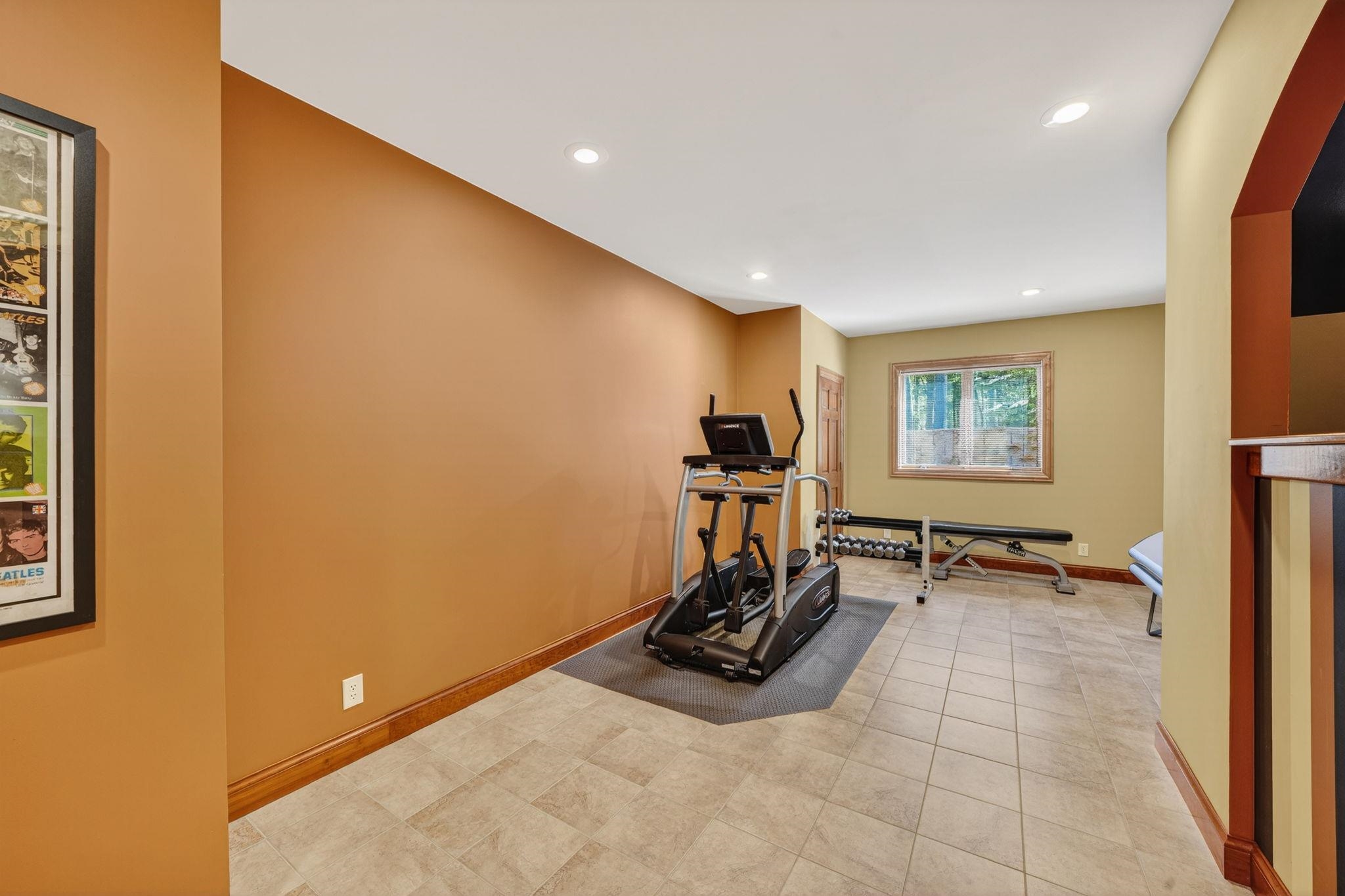Open space featuring tile flooring, recessed lighting, a wood-trimmed window, and a built-in arched alcove